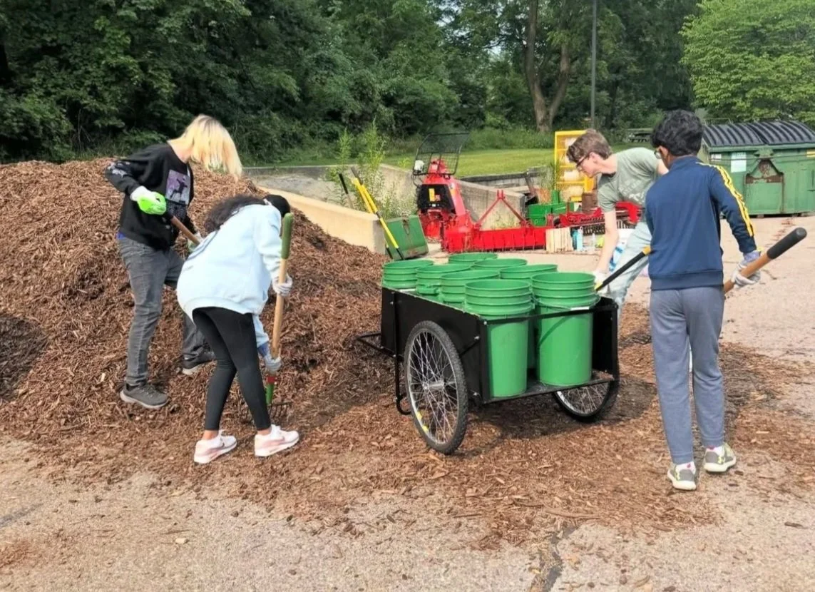 Audience members seated in a row, holding notebooks and pens, attending a presentation or conference.