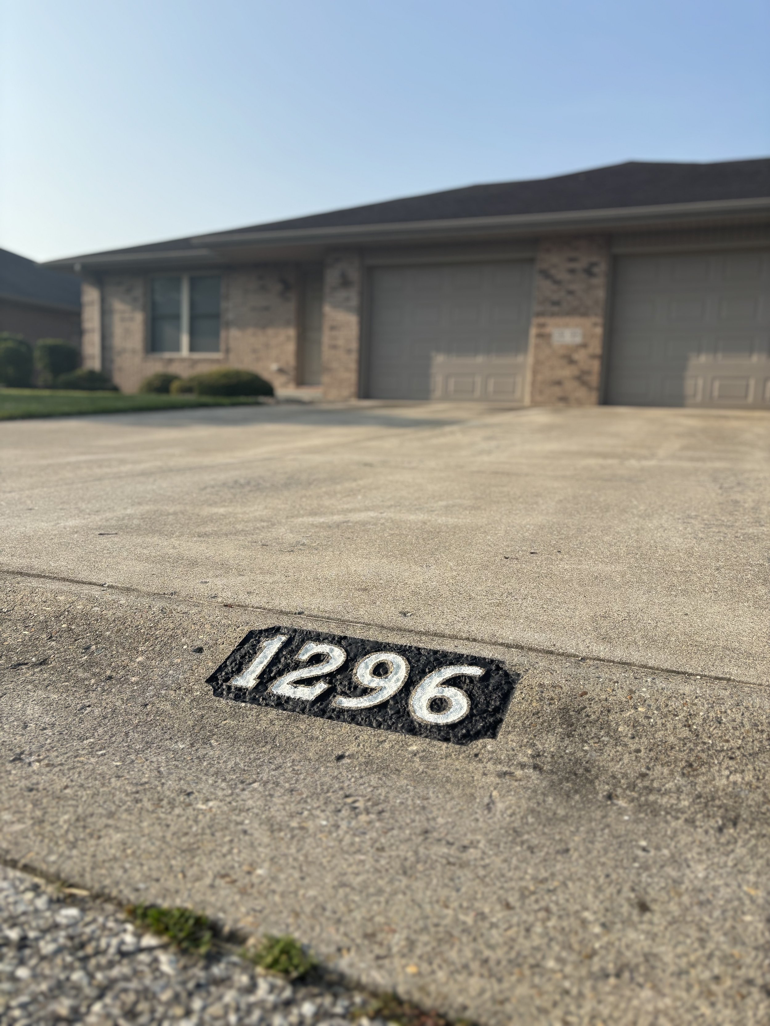 Reflective curb address sign for house number 1296, installed on concrete by Clear Vision Curbs to improve emergency response and nighttime visibility.
