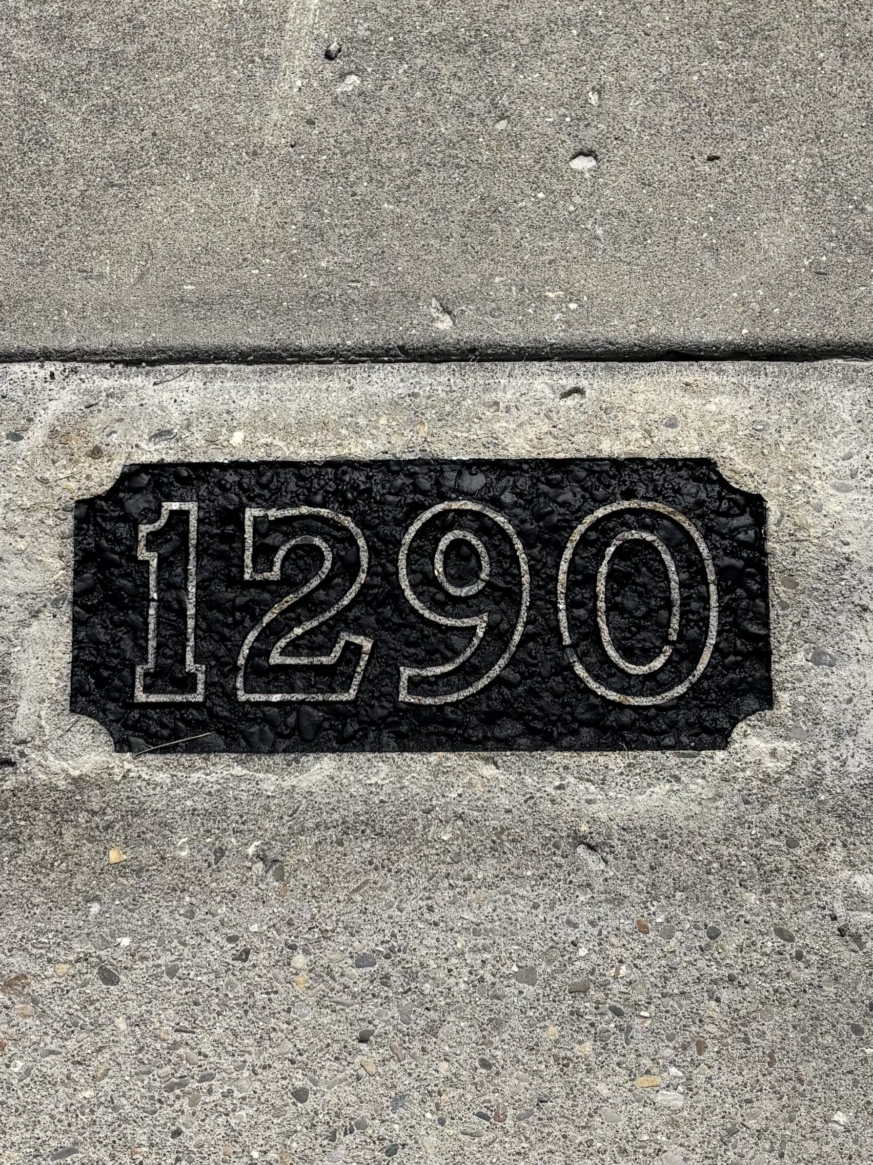 Image of freshly painted black curb address numbers, showcasing a clear, high-contrast street number application using outdoor-grade paint.