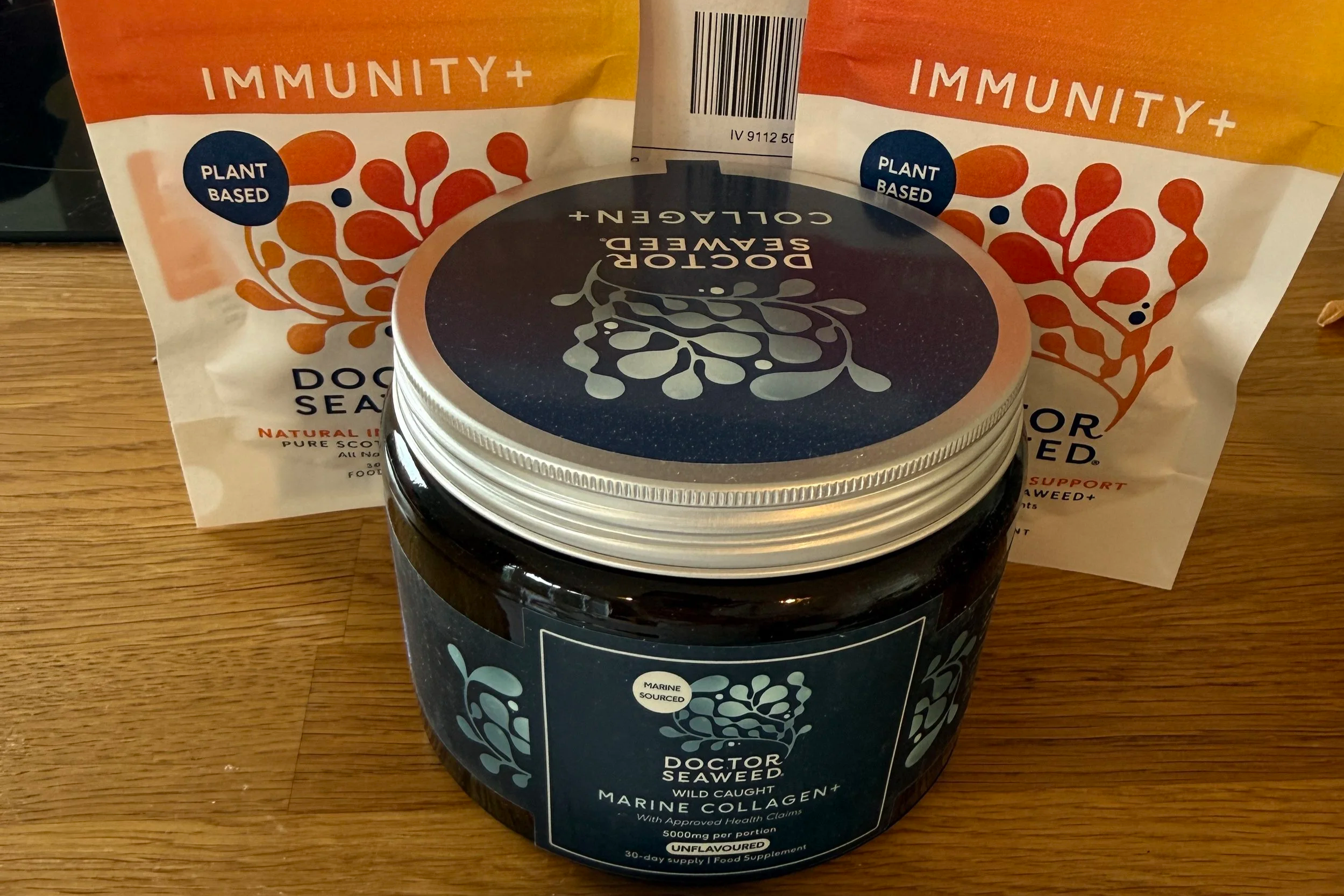 Two packages of plant-based immunity supporting supplements, one labeled 'Doctor Seaweed' with marine sourced marine collagen, and the other labeled 'Doctor Seaweed' with seaweed ingredients, placed on a wooden surface.