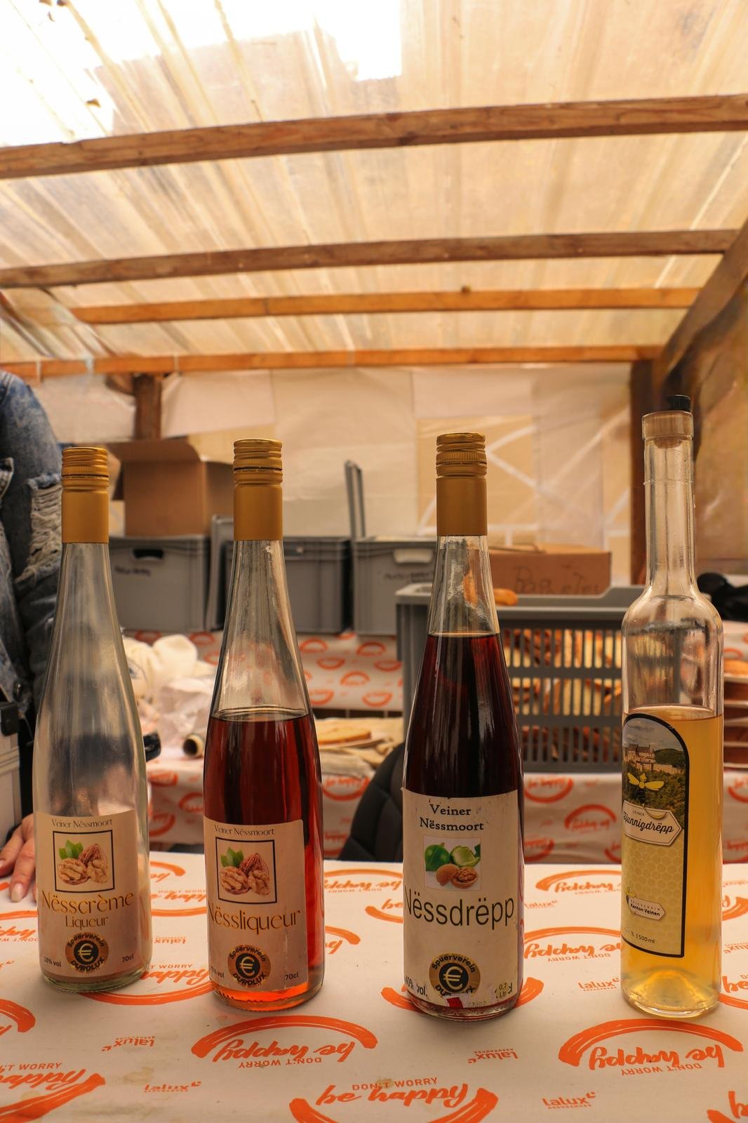 Four bottles with various liquids on a table, with a wooden ceiling in the background.