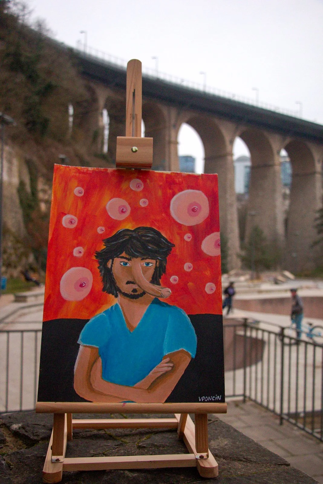 Painting of a man with arms crossed, wearing a blue shirt with a nose and head shaped like a fish, set against a red background with pink bubbles.