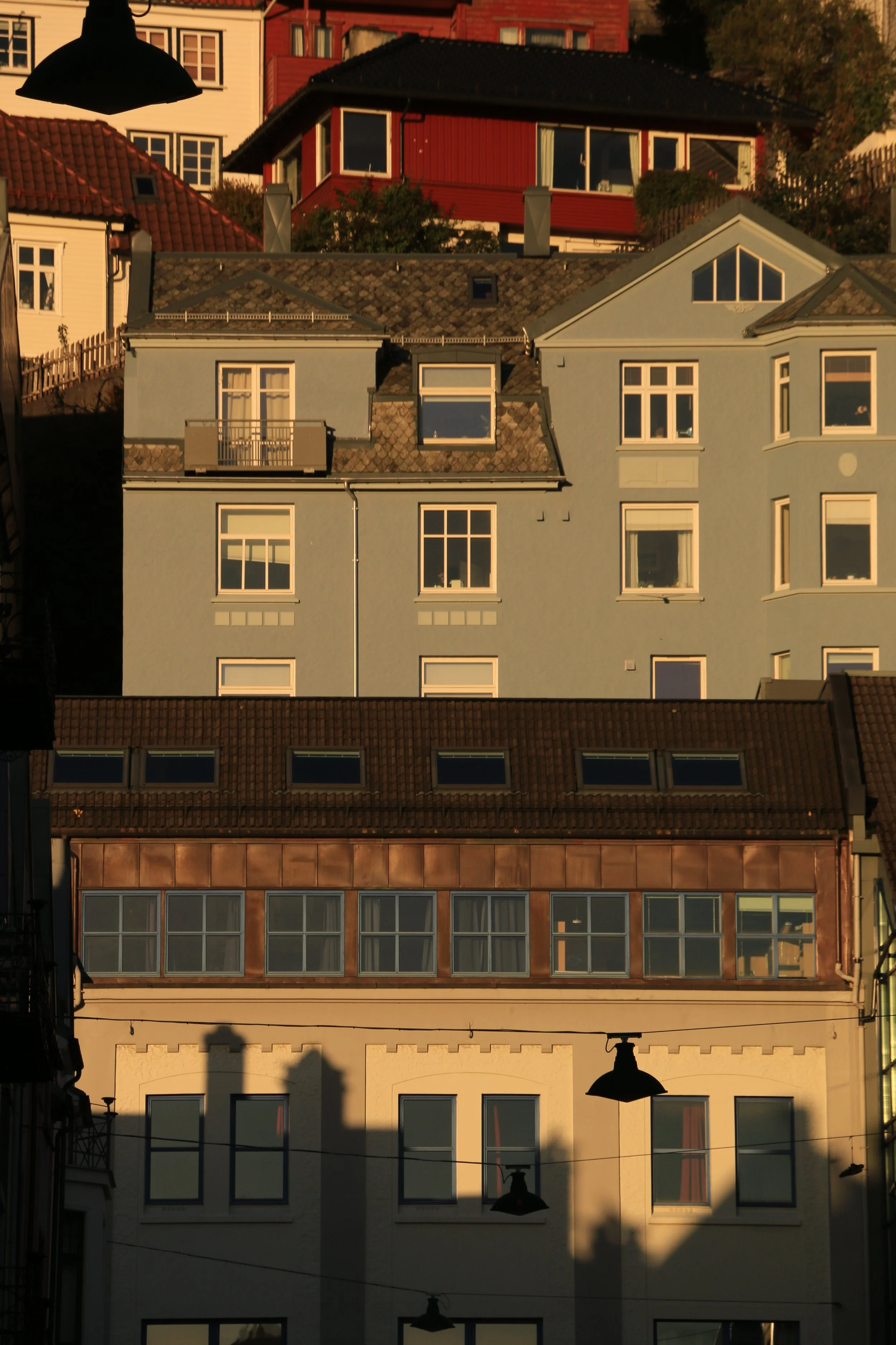 Multiple colorful residential buildings on a hill at sunset.