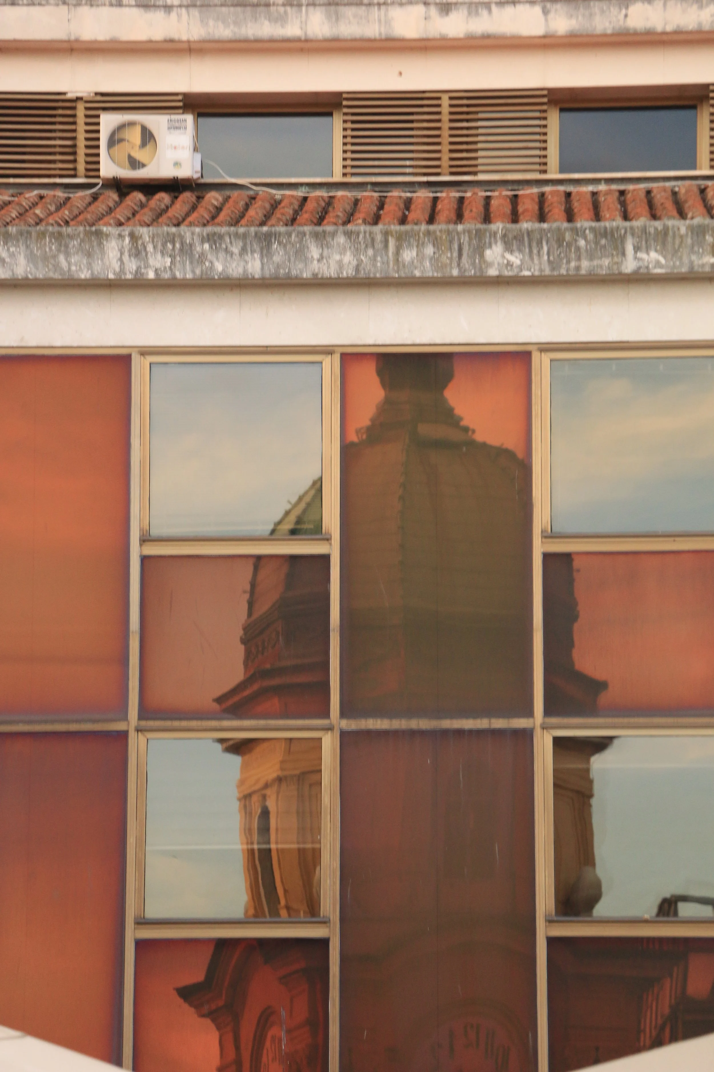 Reflection of a historic building with a dome and architecture in the glass windows of a modern building.