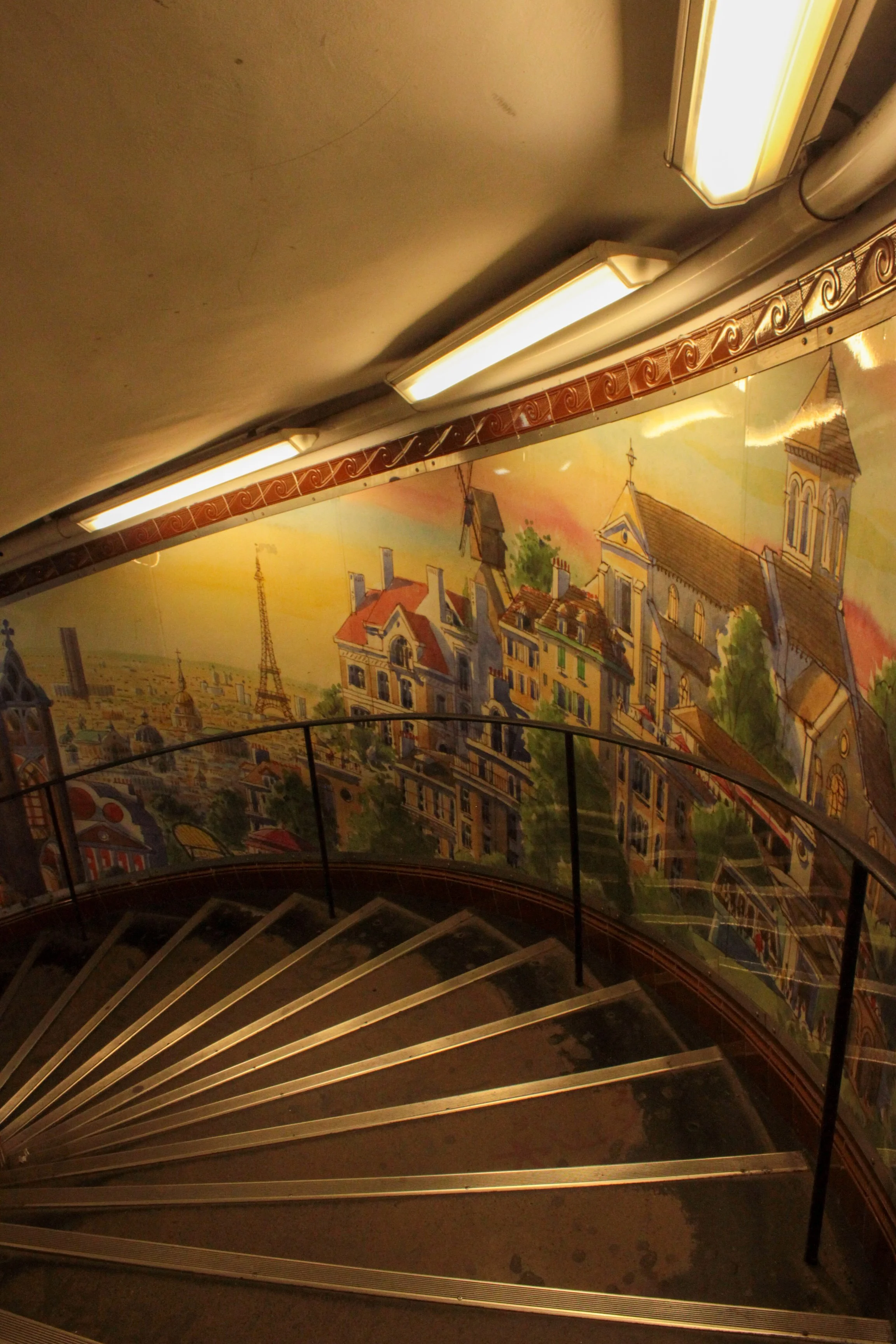 Decorative staircase with mural depicting Parisian cityscape, including Eiffel Tower and historic buildings.