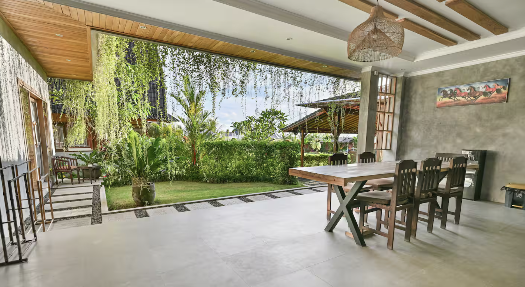 Houses with tiled roofs surrounded by lush tropical plants and trees in a hilly area.