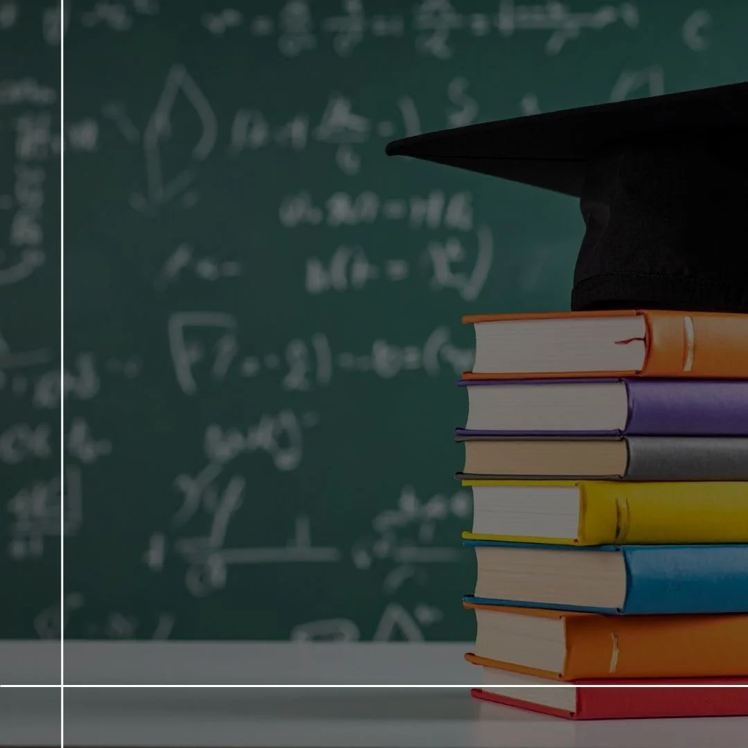 Stack of colorful books with a graduation cap on top, in front of a chalkboard filled with math equations.