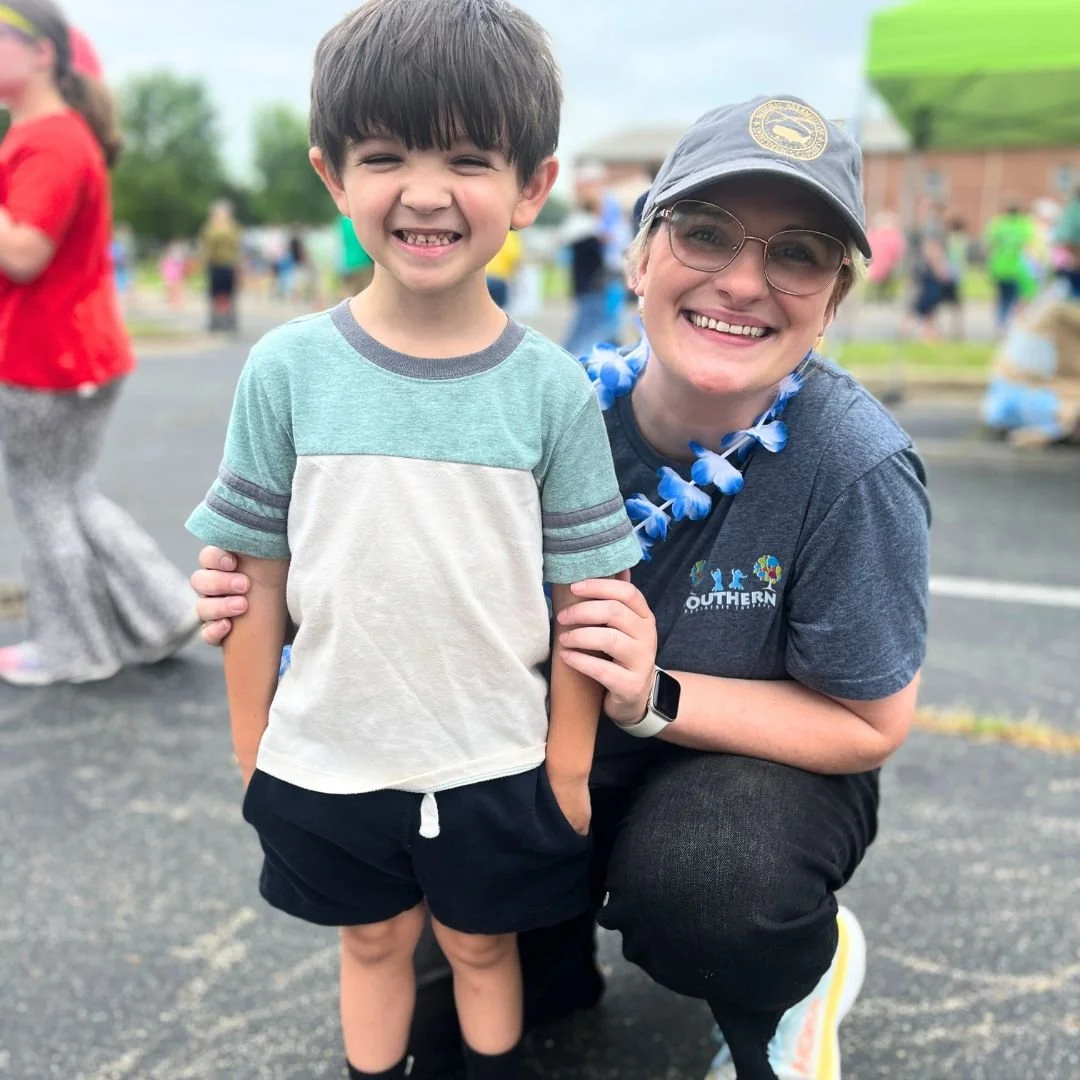 Therapist and child hugging and smiling during an outdoor event