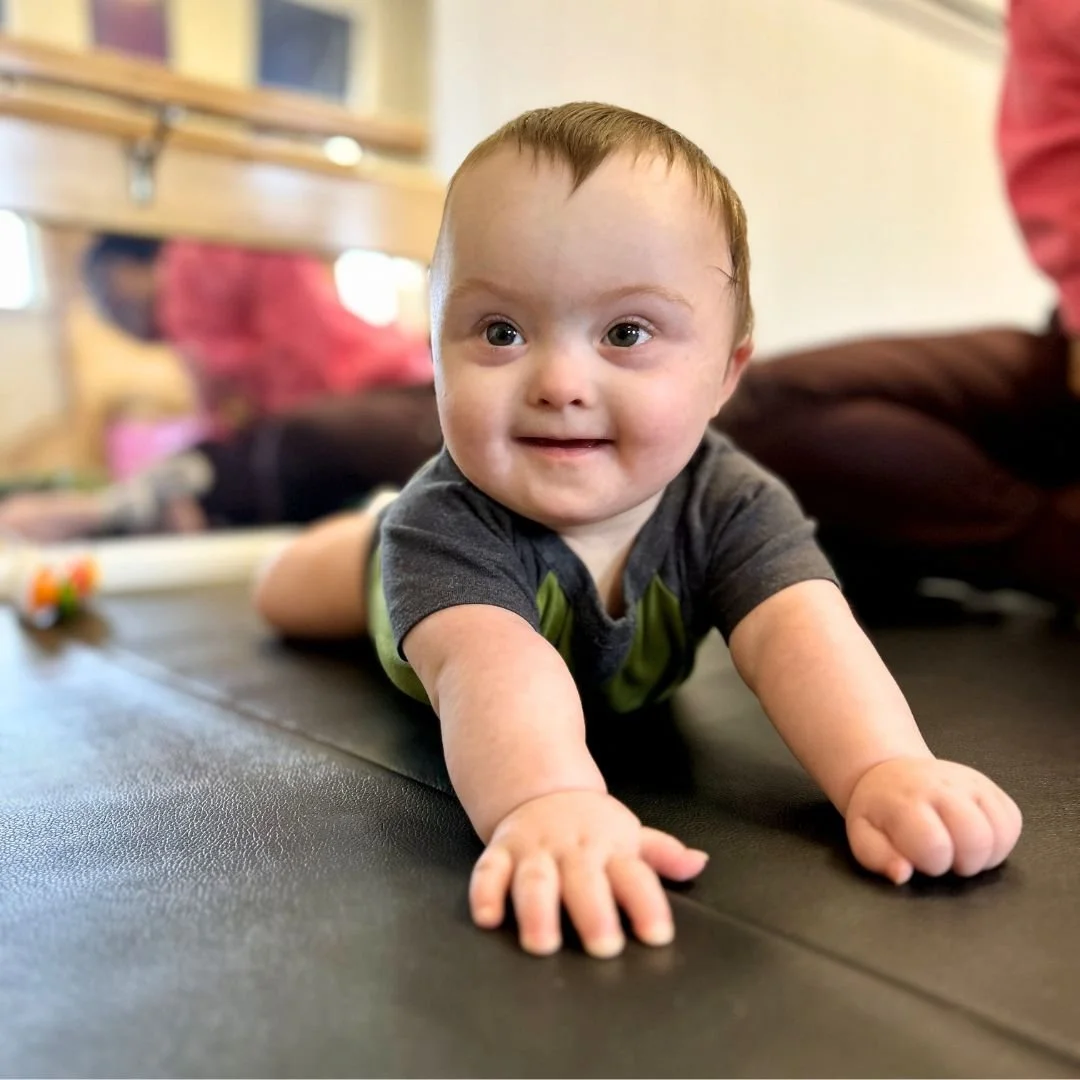 Baby doing tummy time on the floor and smiling during physical therapy at Southern Pediatric Therapy