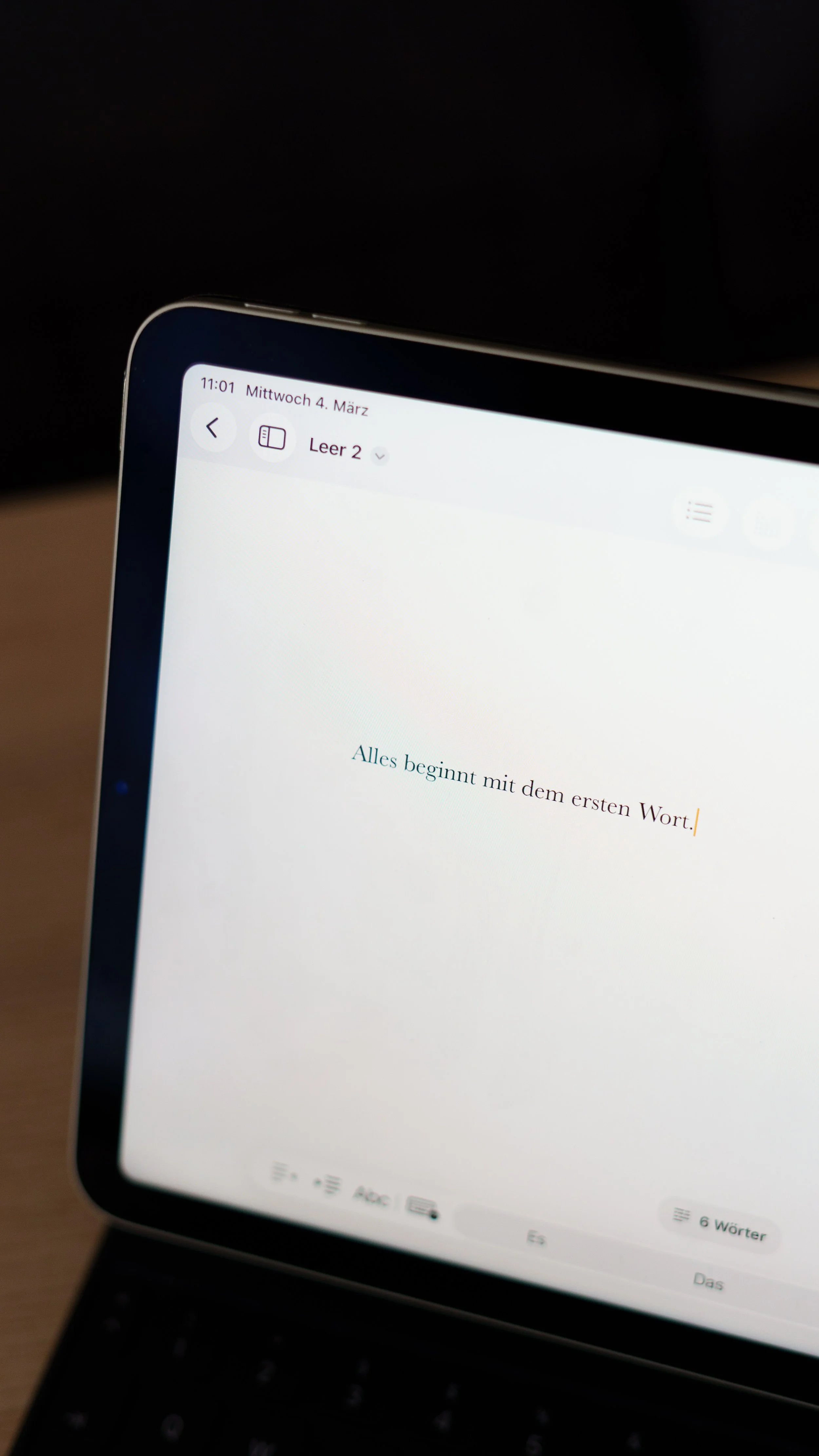 Ein Laptop-Bildschirm zeigt einen Text in deutscher Sprache: "Alles beginnt mit dem ersten Wort."