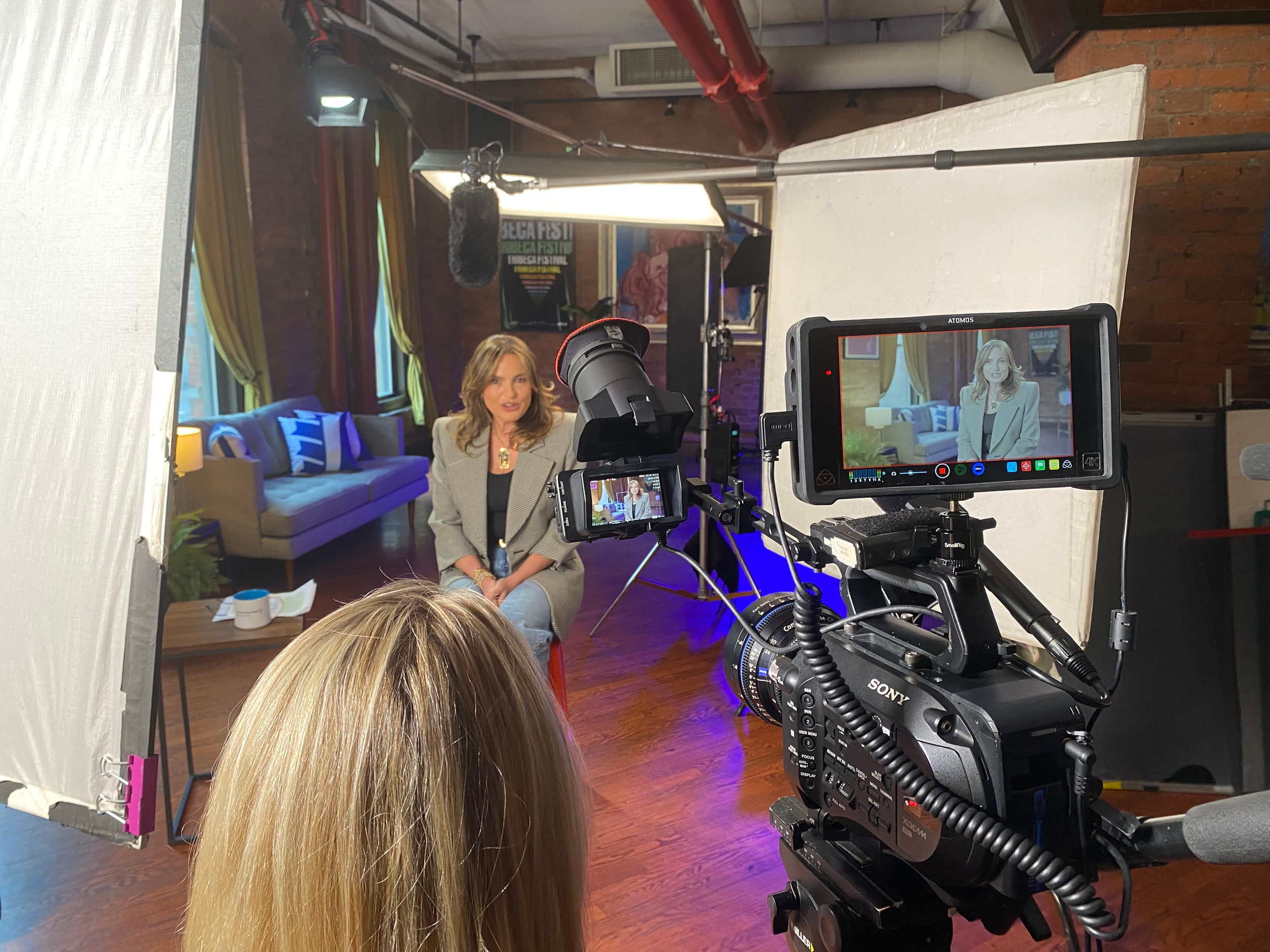 Woman being filmed in a TV studio with professional lighting and camera equipment.