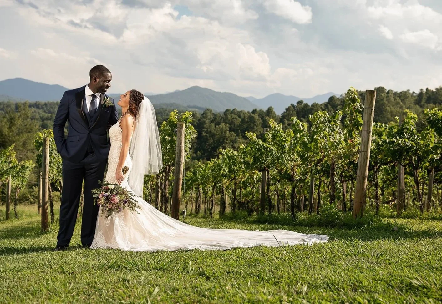 Bride and groom standing in a vineyard with Blue Ridge Mountain views at a Western North Carolina wedding venue.