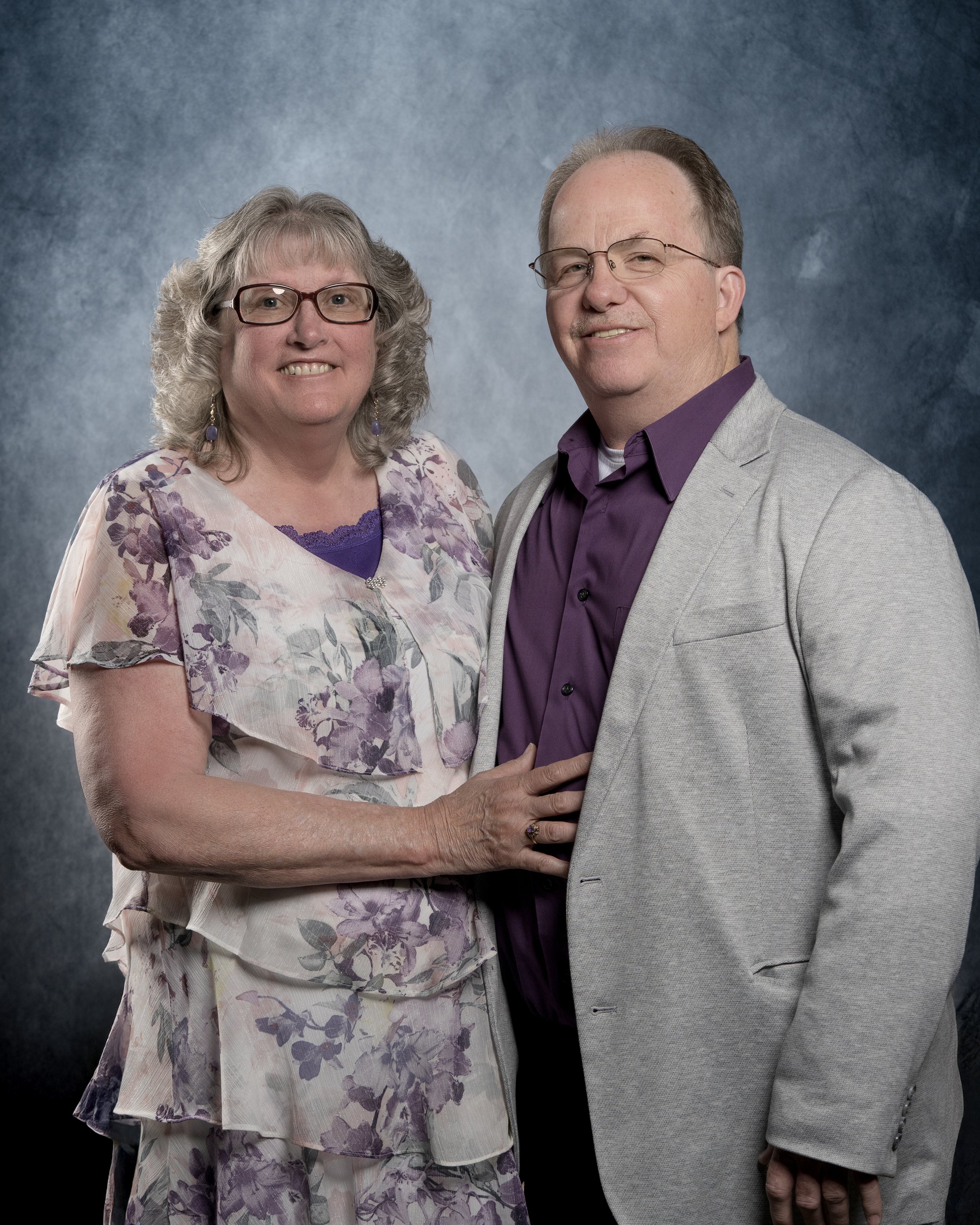 Older couple posing in front of a green background