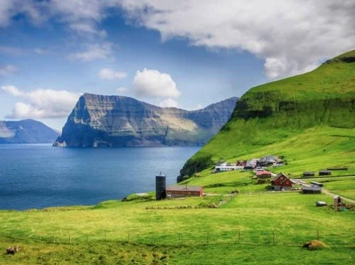 Scenic coastal landscape with green hills, ocean, and village