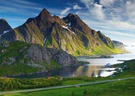 Scenic view of lush green mountains and a calm lake under a clear blue sky.