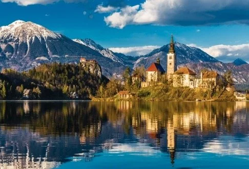 Scenic view of Lake Bled with its island church and surrounding mountains reflecting in the water.