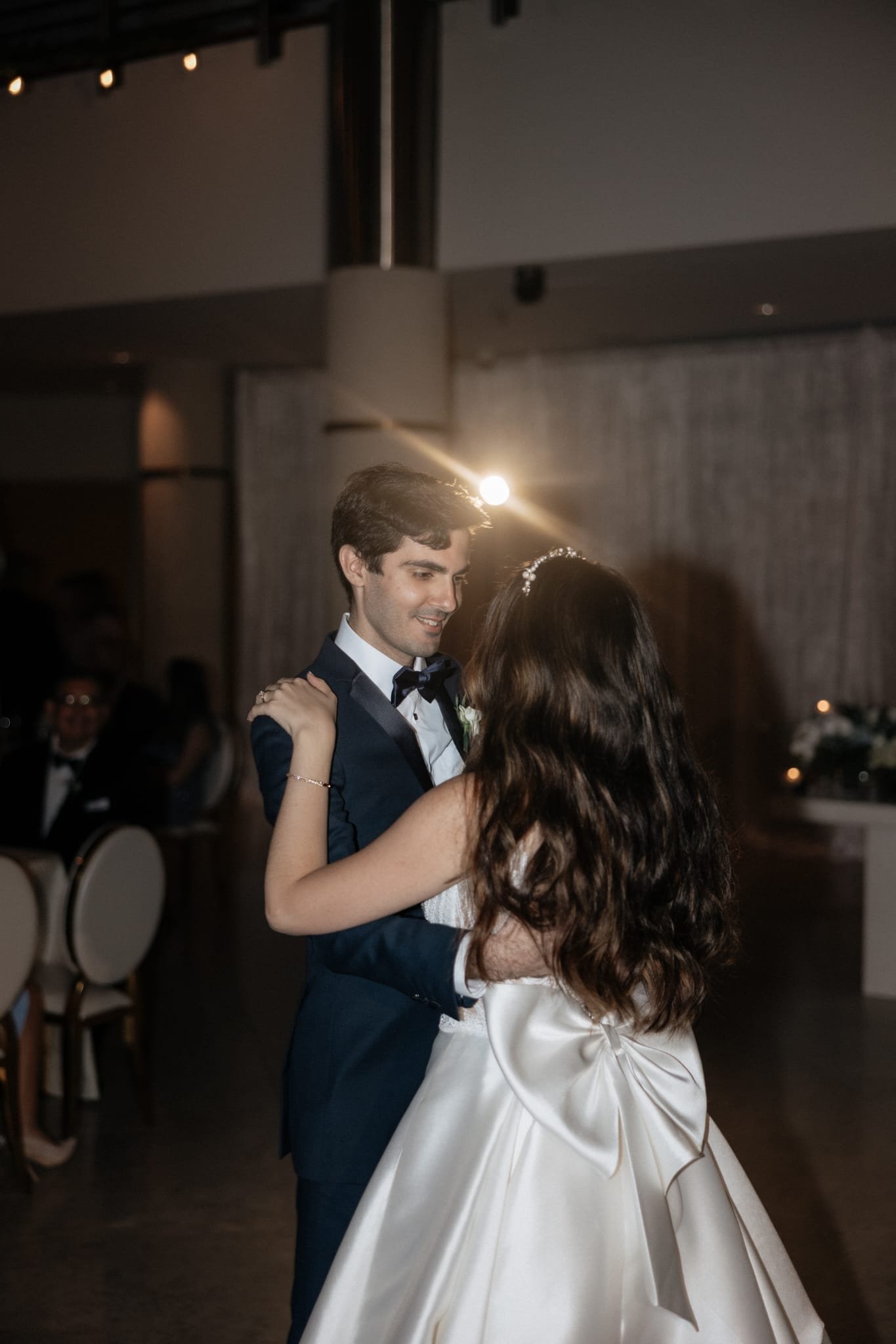 A newlywed couple dancing at their wedding reception, with the groom in a tuxedo and the bride in a white wedding gown.