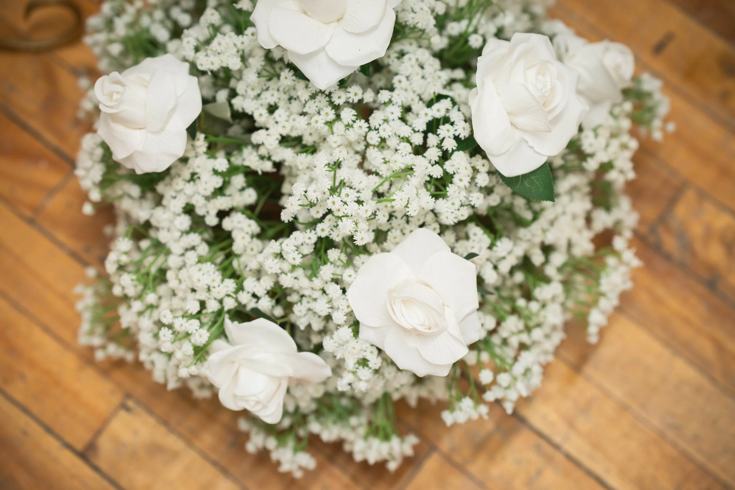 A bouquet of white roses and small white flowers on a wooden surface.