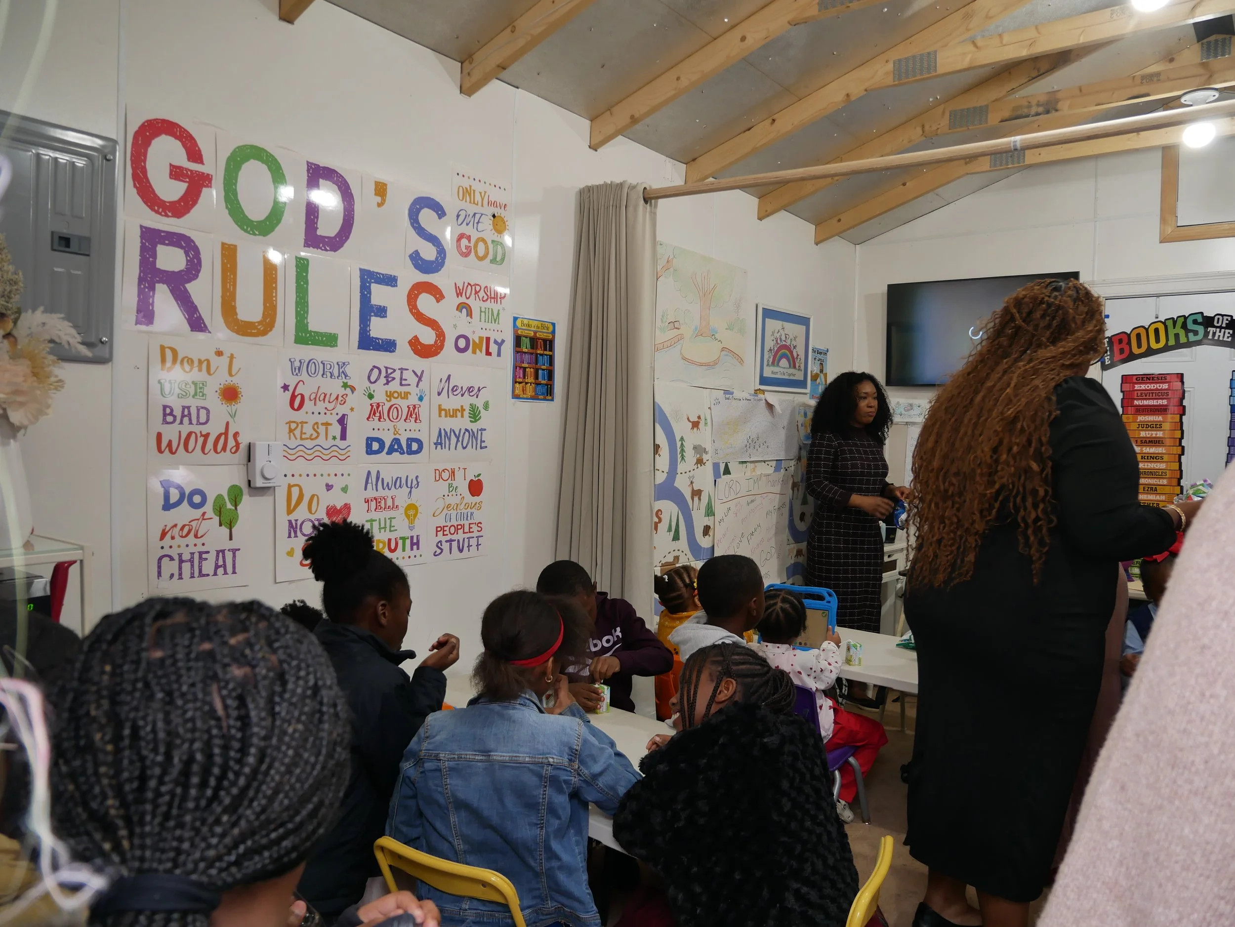 Children sitting at a table engaged in coloring activities during a classroom event, with art supplies on the table.