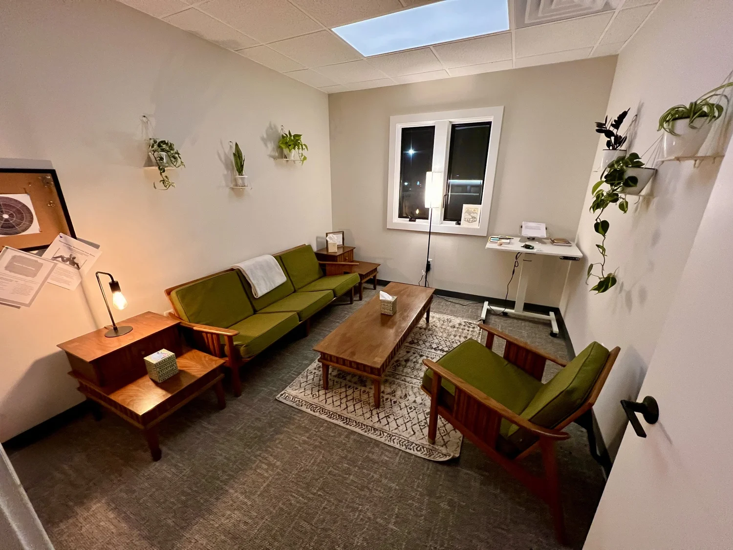 Michael’s therapy office in Grand Rapids with a green sofa, armchair, plants, and a skylight