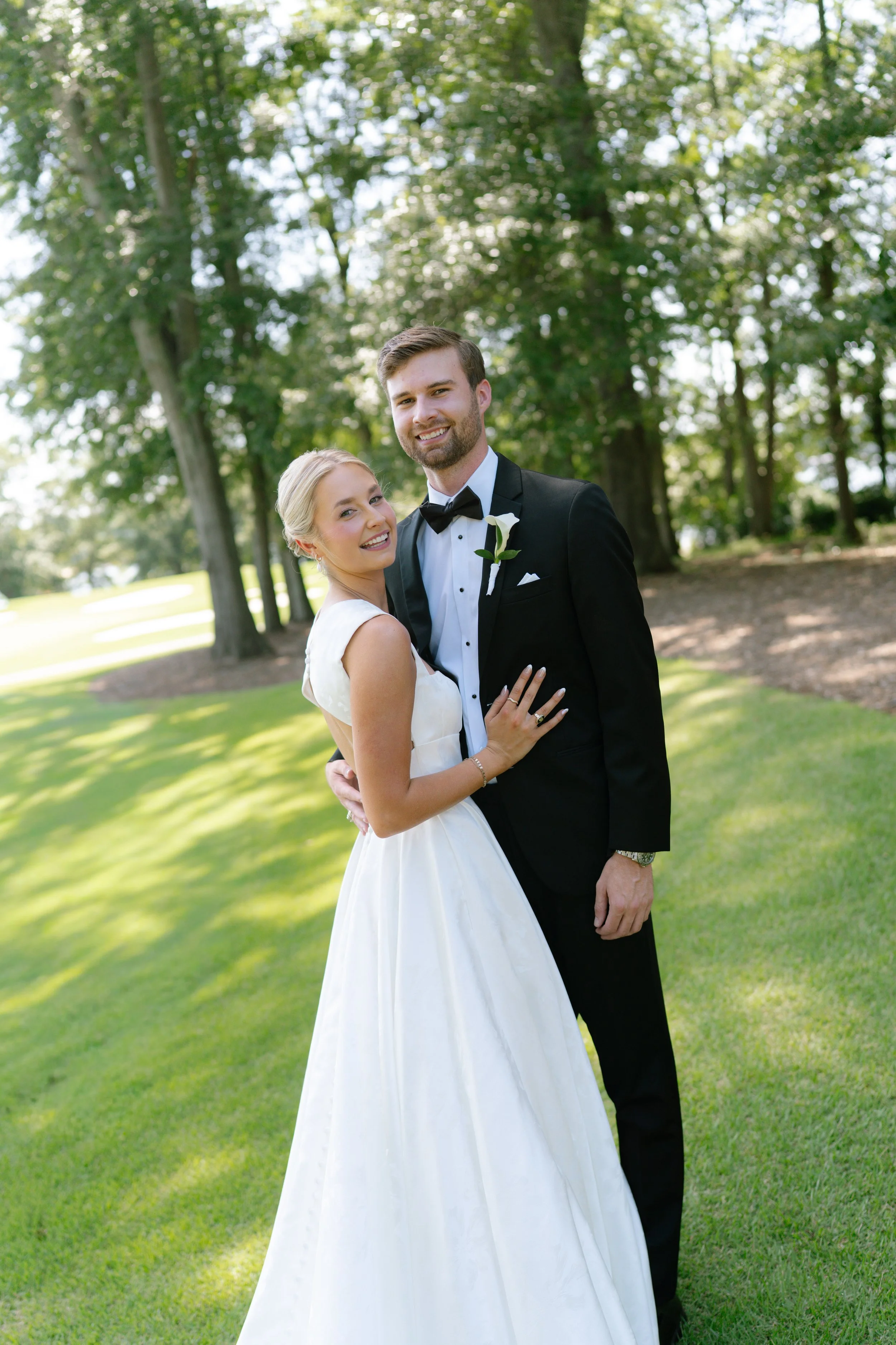 Bride and groom embracing on Clemson University golf course during outdoor wedding, Clemson SC wedding photographer
