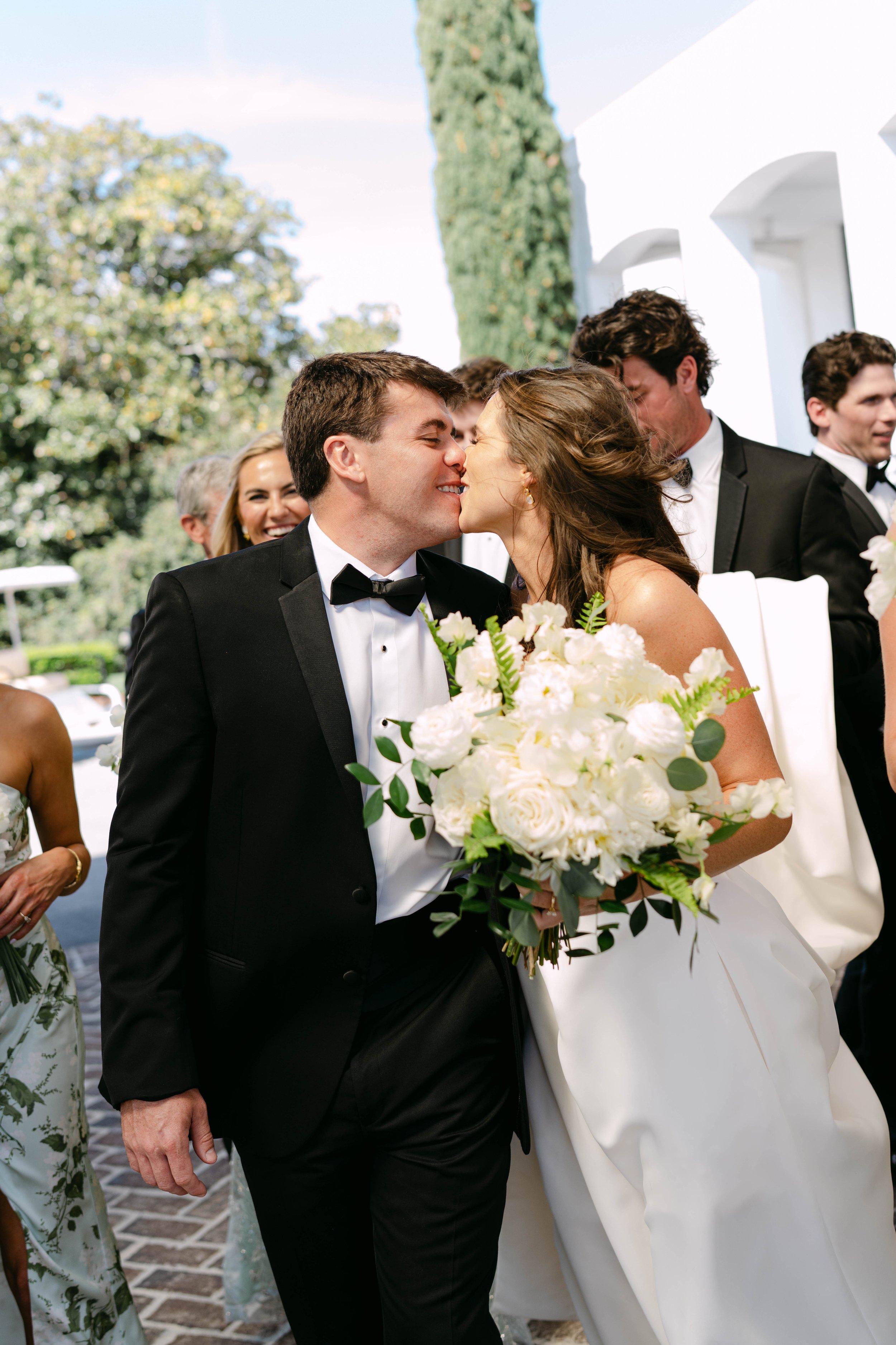 Bride and groom sharing a kiss during their wedding recessional surrounded by cheering guests, captured by Columbia SC wedding photographer Chandler Cox