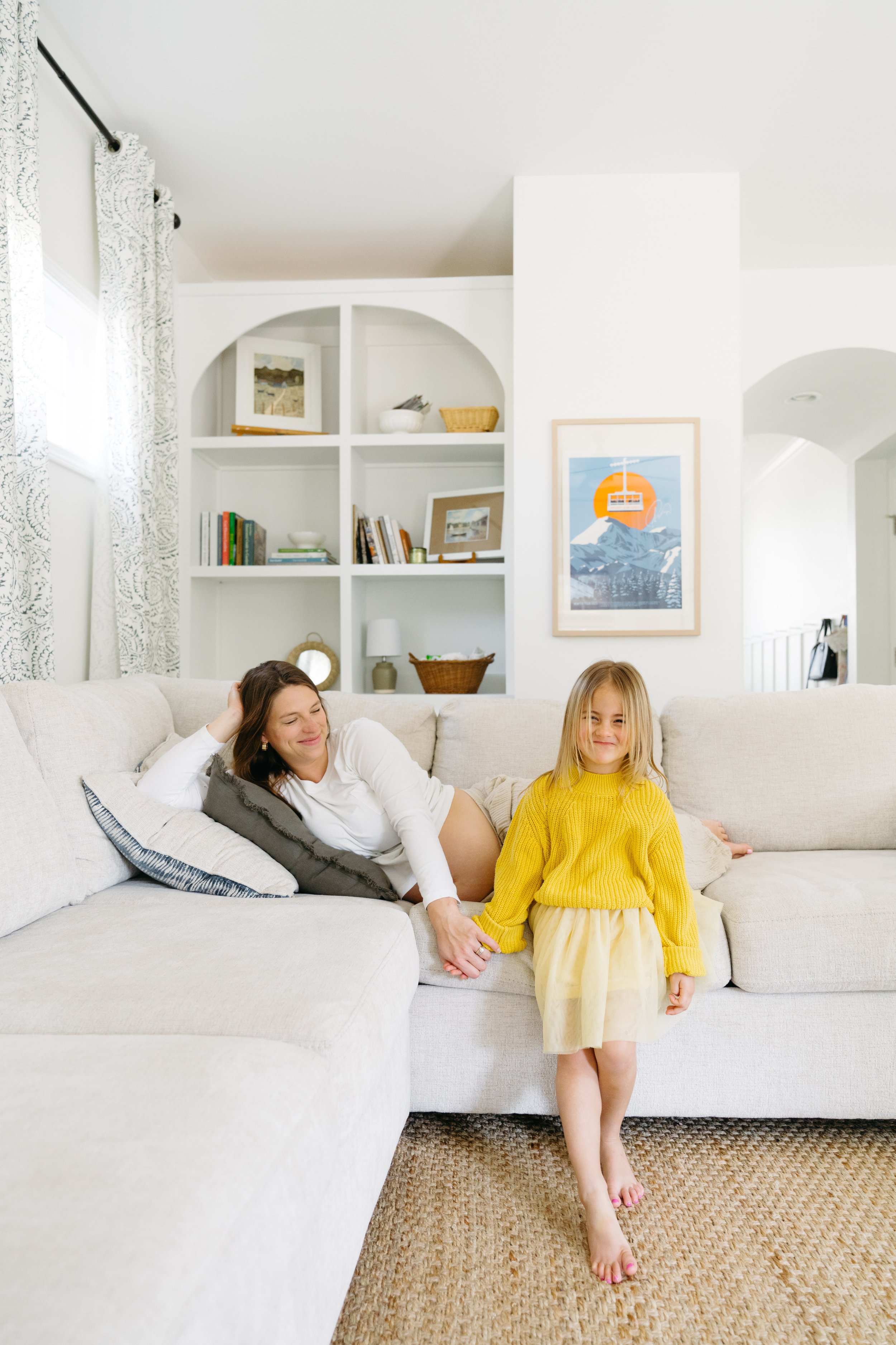 Lifestyle family photography by Chandler Cox — mother and daughter laughing together on cream sectional sofa at home, Columbia SC lifestyle and family portrait photographer