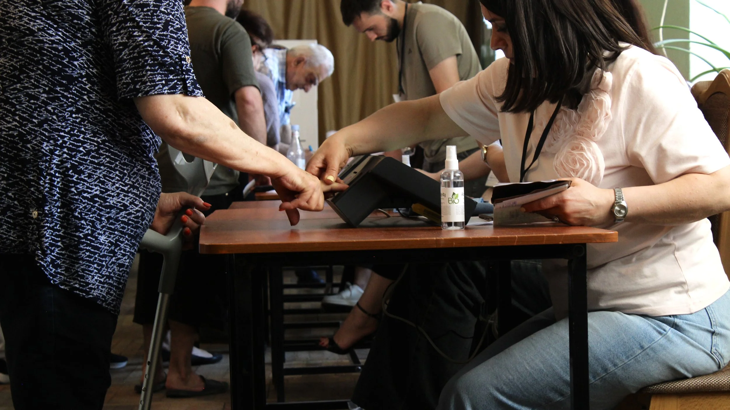 A woman helps a voter sign in to vote at a polling site in Sari Tagh, in south Yerevan on June 7, 2026.