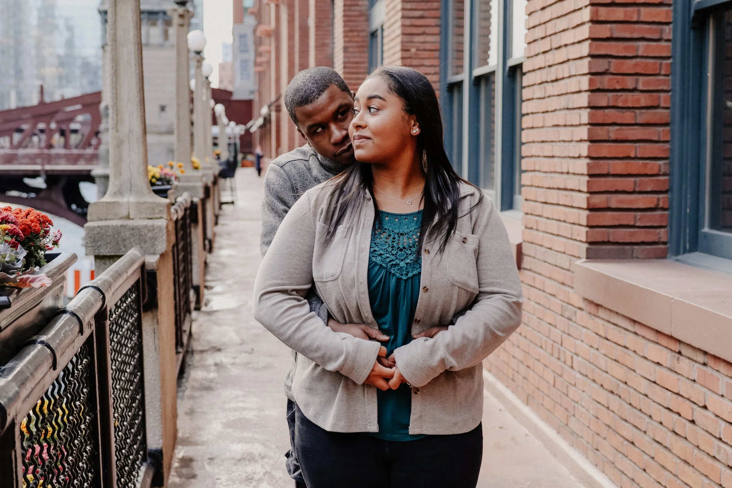 A woman and man stand near a brick building to take engagement photos in Chicago, IL.