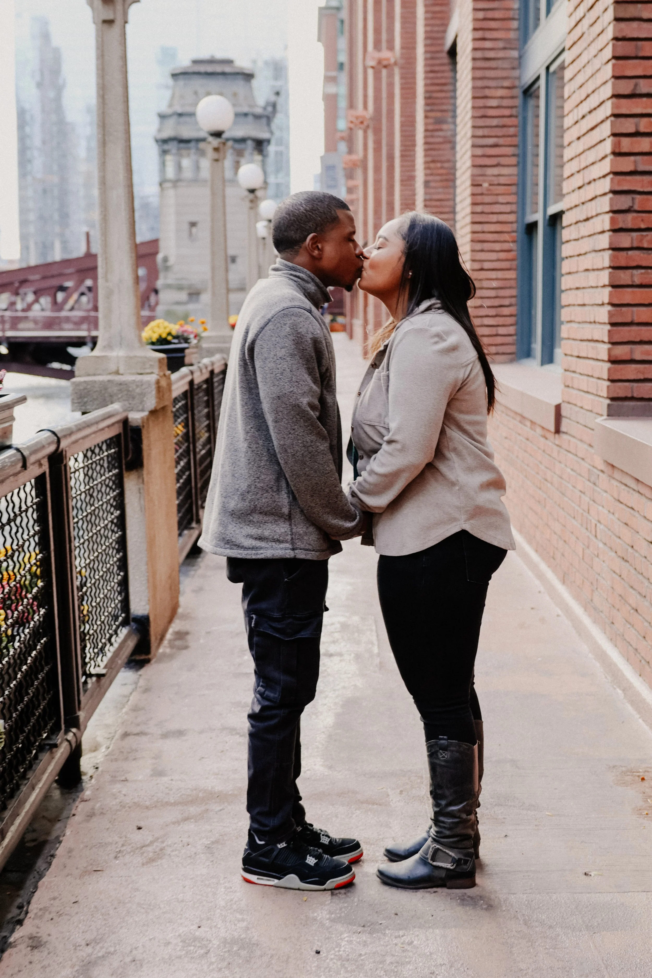 A couple takes engagement photos in Chicago in River North with a brick building and river as backdrop.