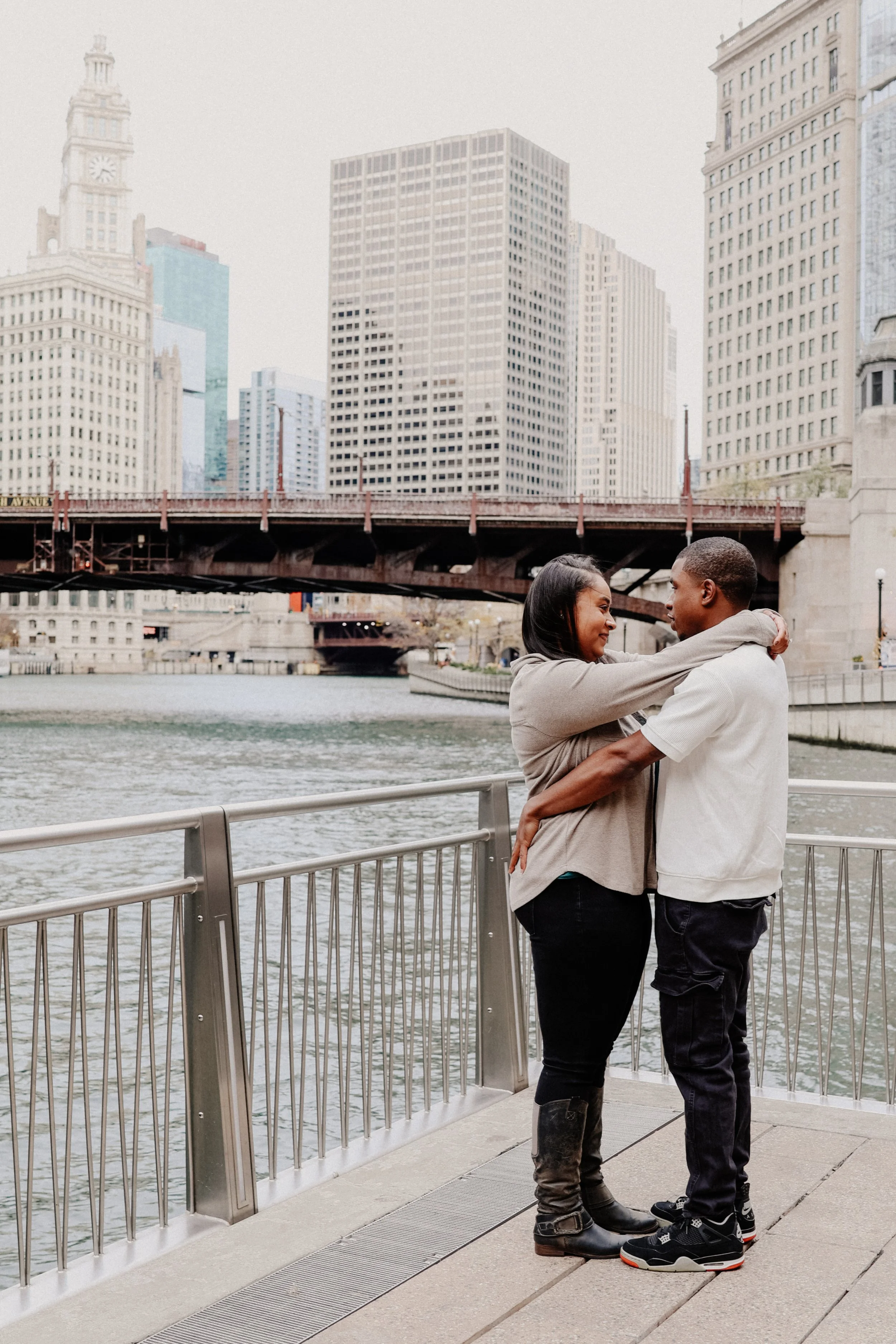 A couple embraces while standing near the river in Chicago downtown.