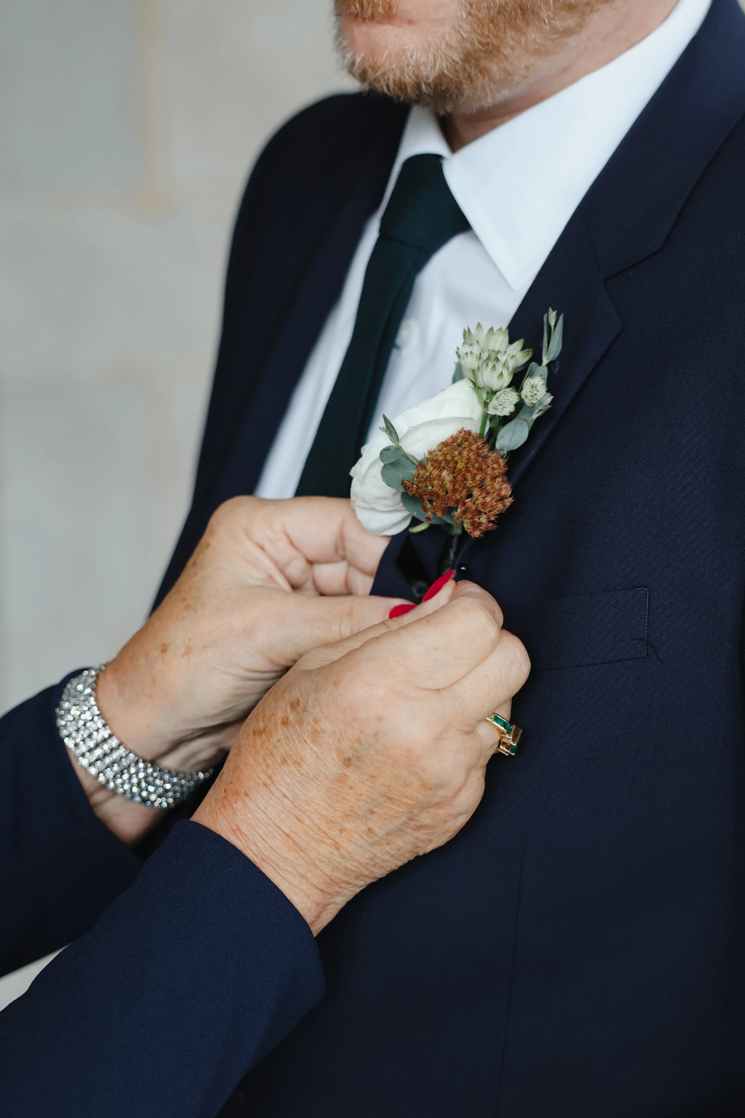 A groom has his boutonnière pinned on his lapel by his mother at Michigan Shores Club in Wilmette, IL.