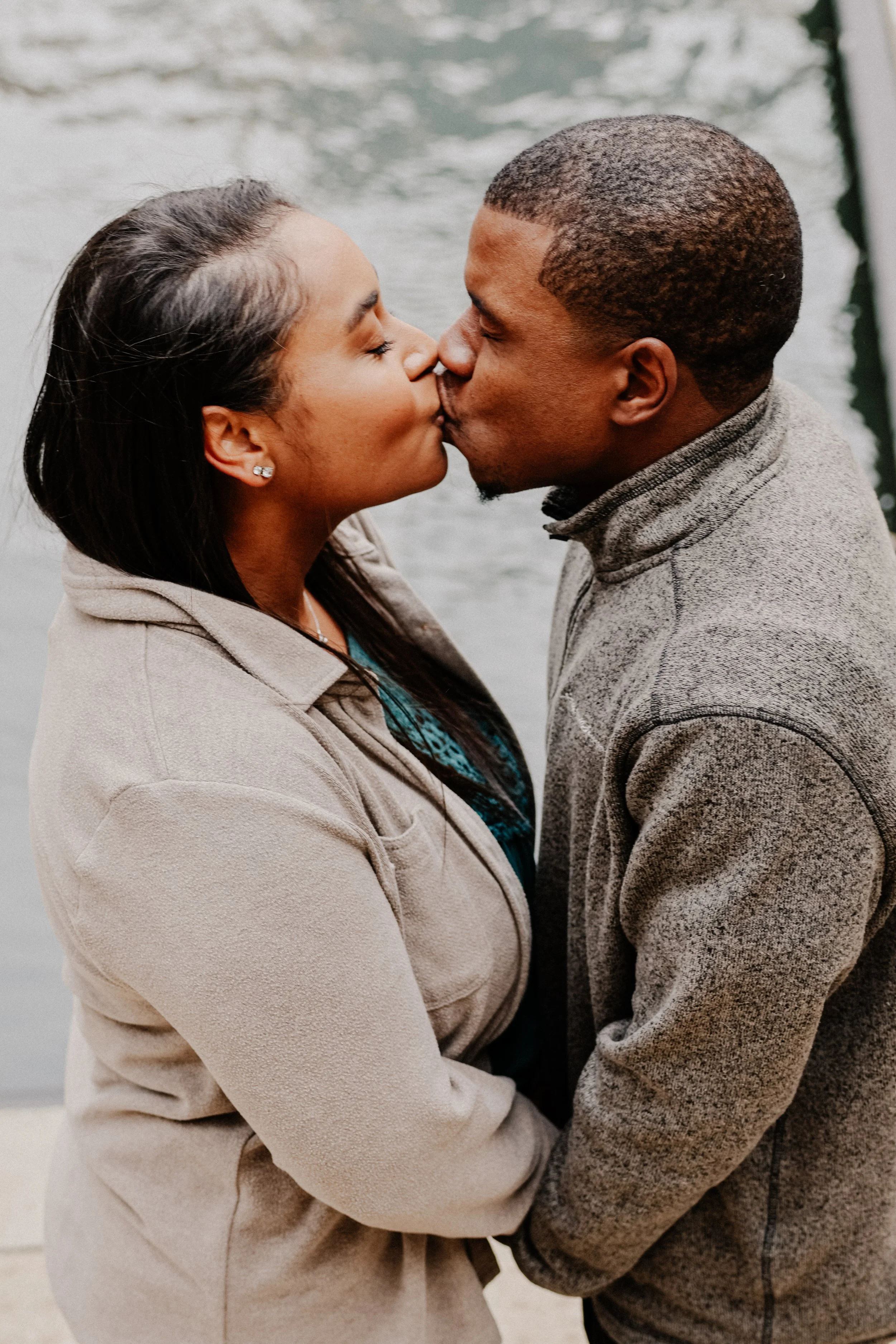 A couple kisses along the Riverwalk in Chicago as they take an engagement photo.