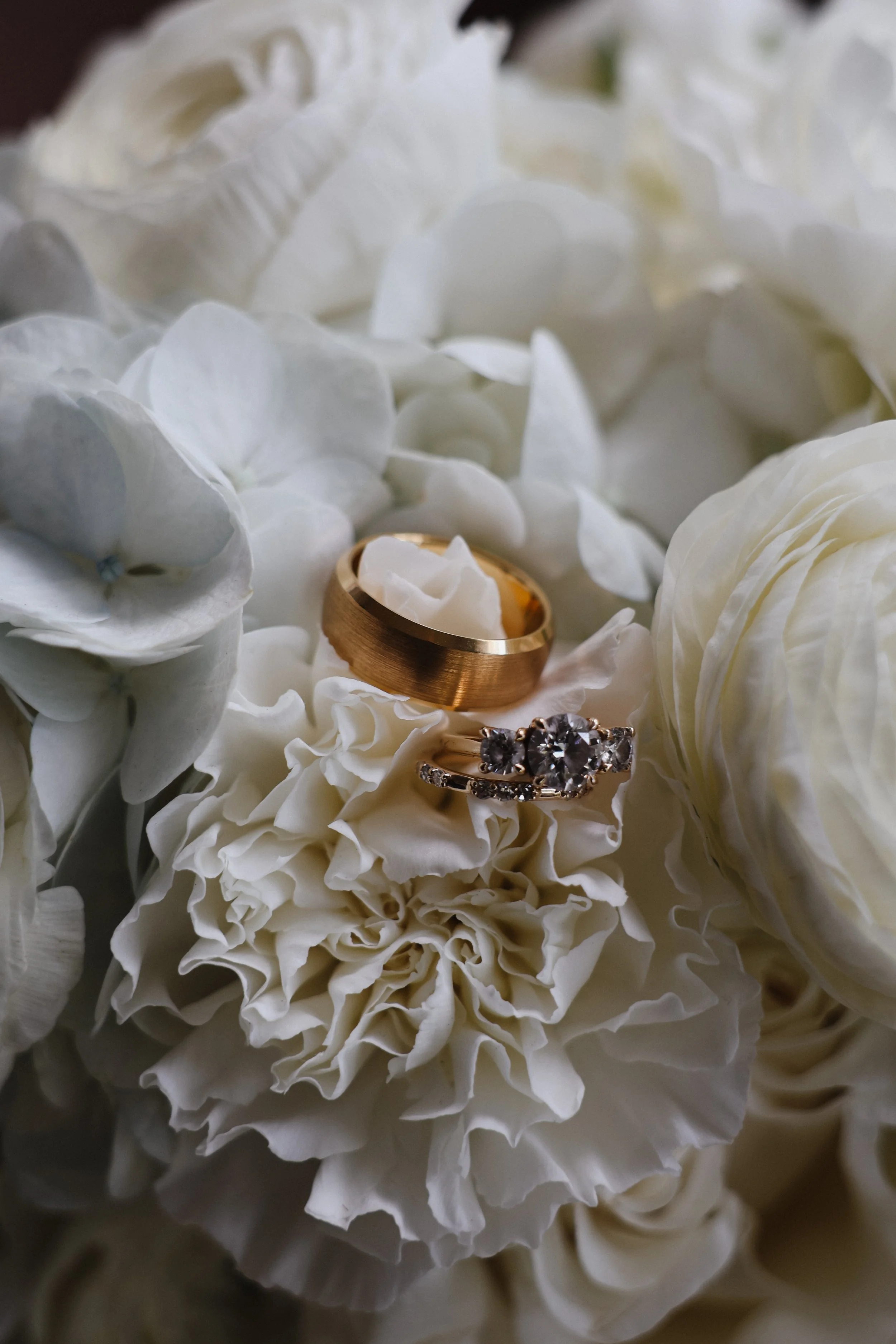 A bride and groom's wedding bands and engagement ring sit atop blooms in a bridge's bouquet in WIlmette, IL.