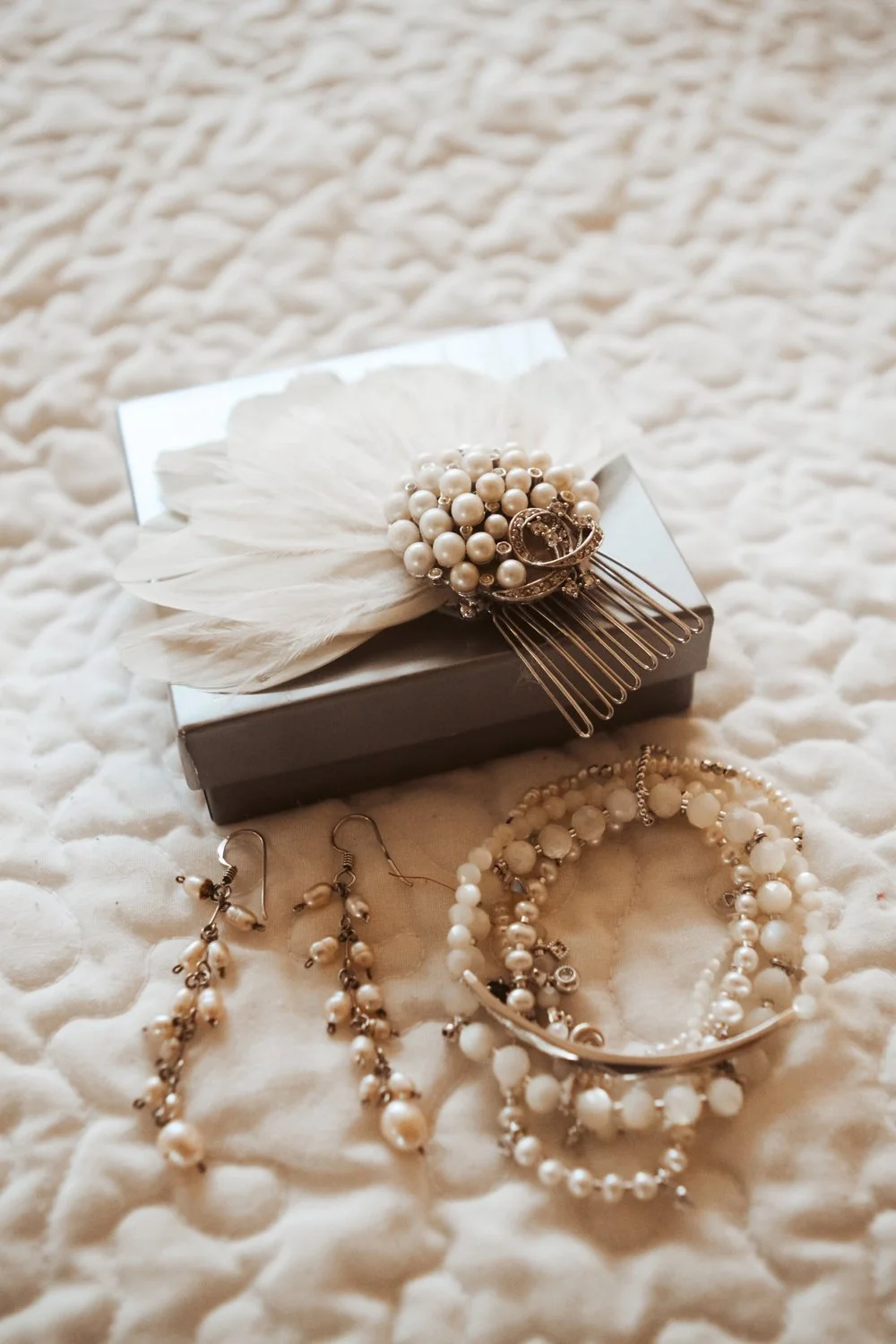 Bridal jewelry for a destination bride complete with pearls, a hair piece, and dangly earrings.