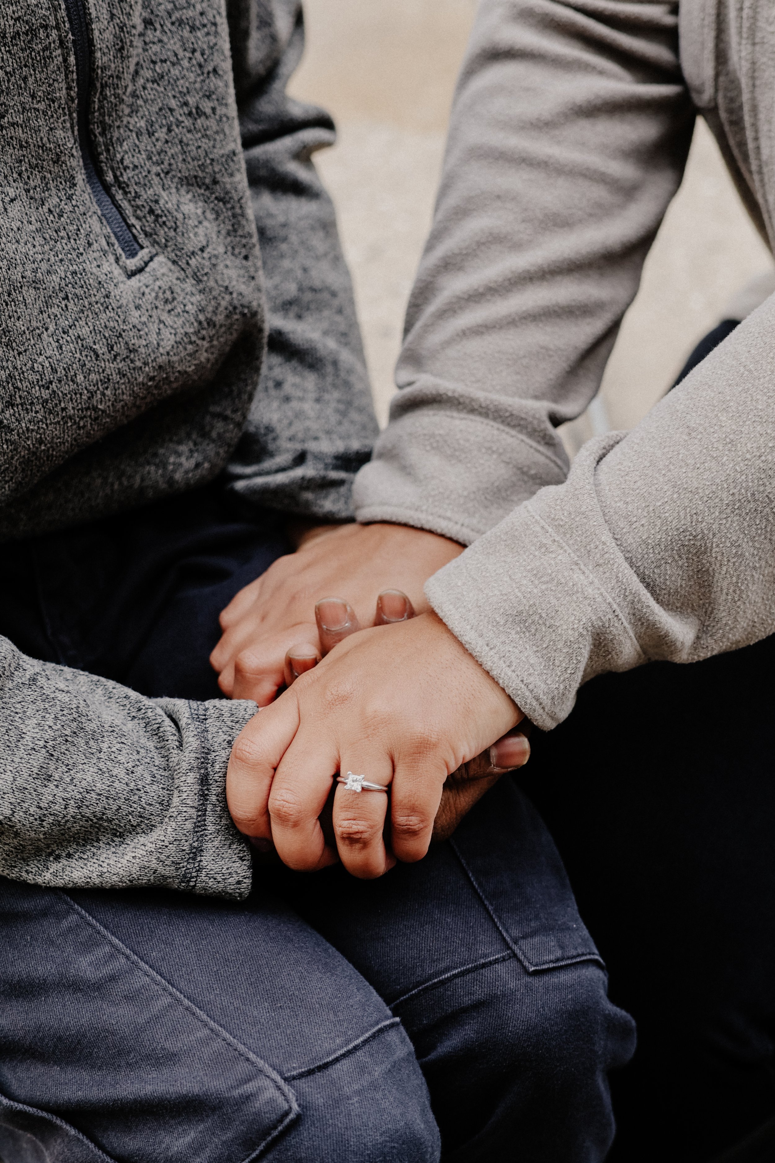 Two people hold hands and pose for a close-up of their hands with engagement ring in Chicago.