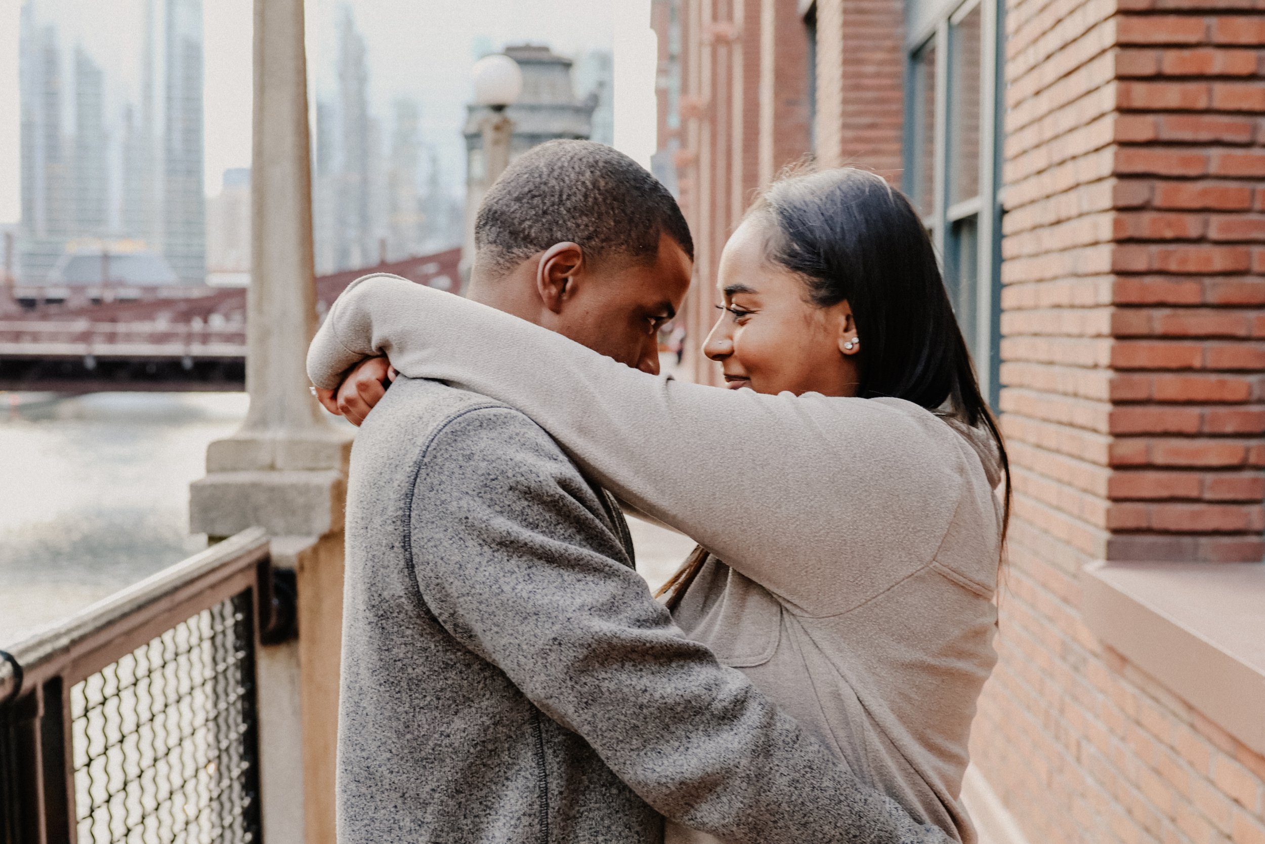 Two people embrace with a brick background in Chicago during engagement photos.