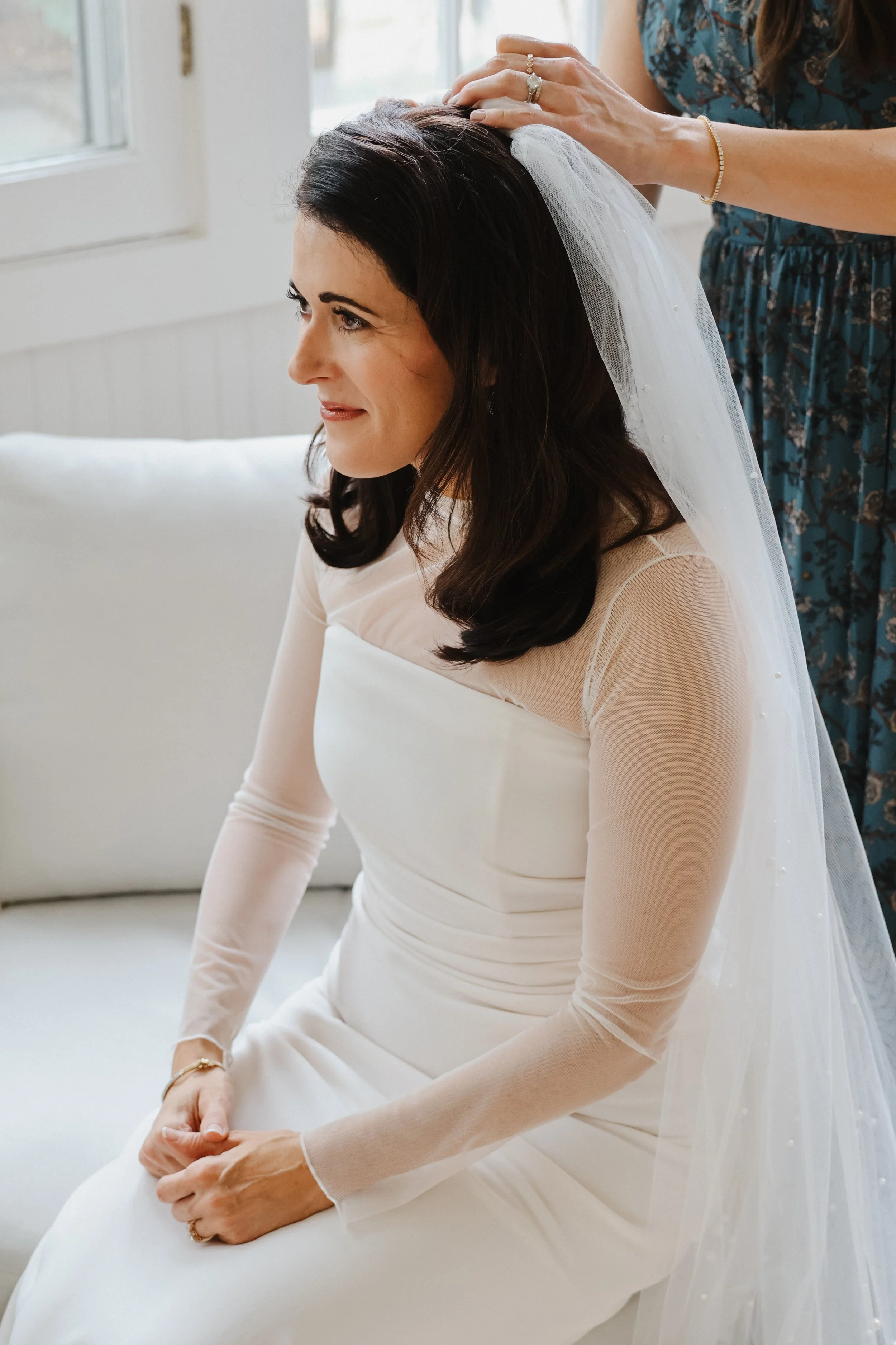 A bride in Wilmette, IL gets her veil pinned on by her sister.