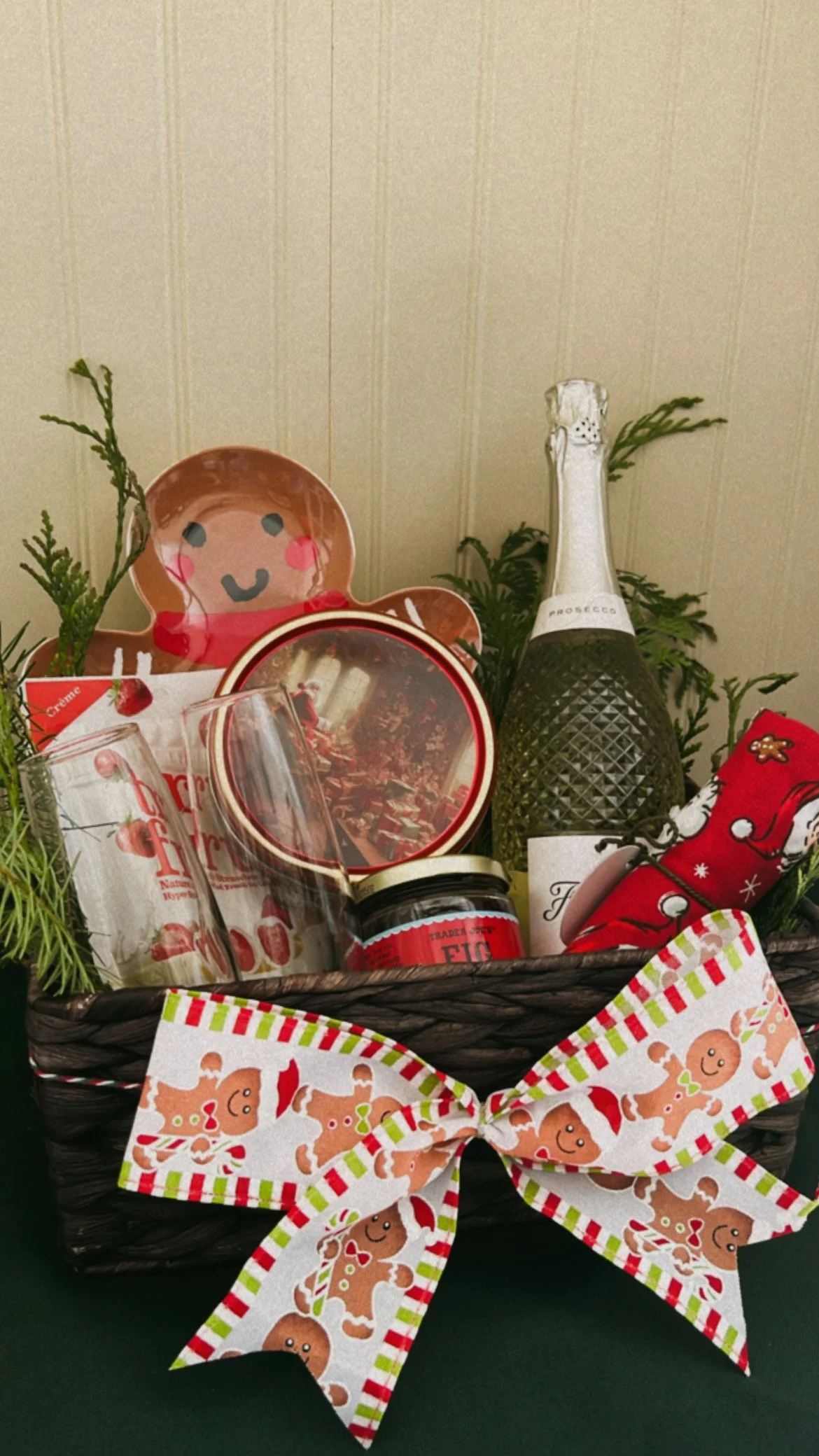 Christmas-themed gift basket with gingerbread man decorations, a bottle of sparkling wine, and holiday treats, all adorned with a festive gingerbread man ribbon.