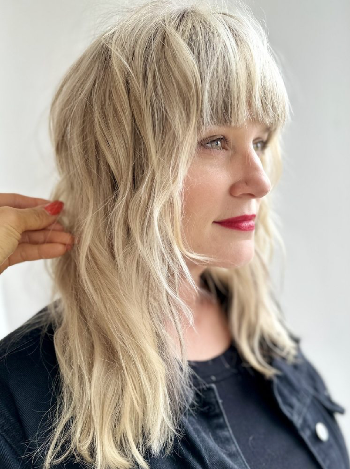 Platinum blonde shag haircut with blunt bangs and textured layers, lived-in icy blonde color by Helen at KH Studio San Francisco.