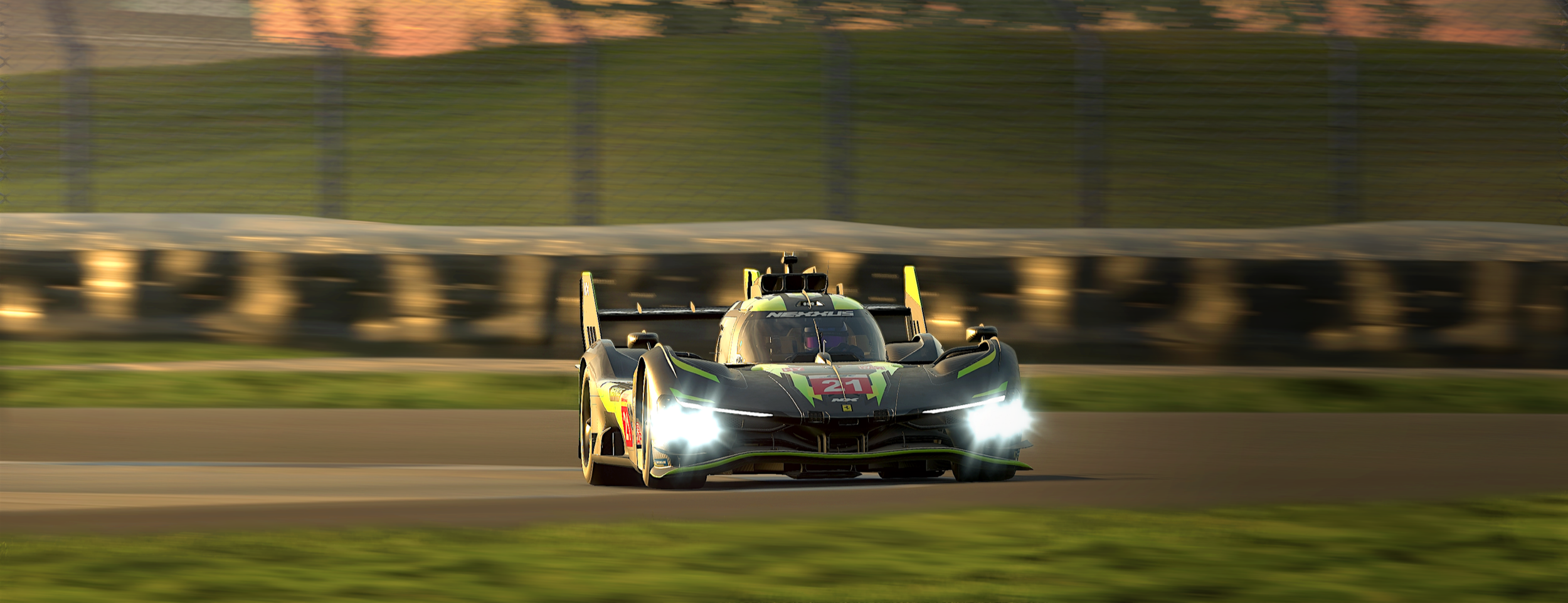 A black and blue race car speeding on a race track during sunset with headlights on and a fenced background.