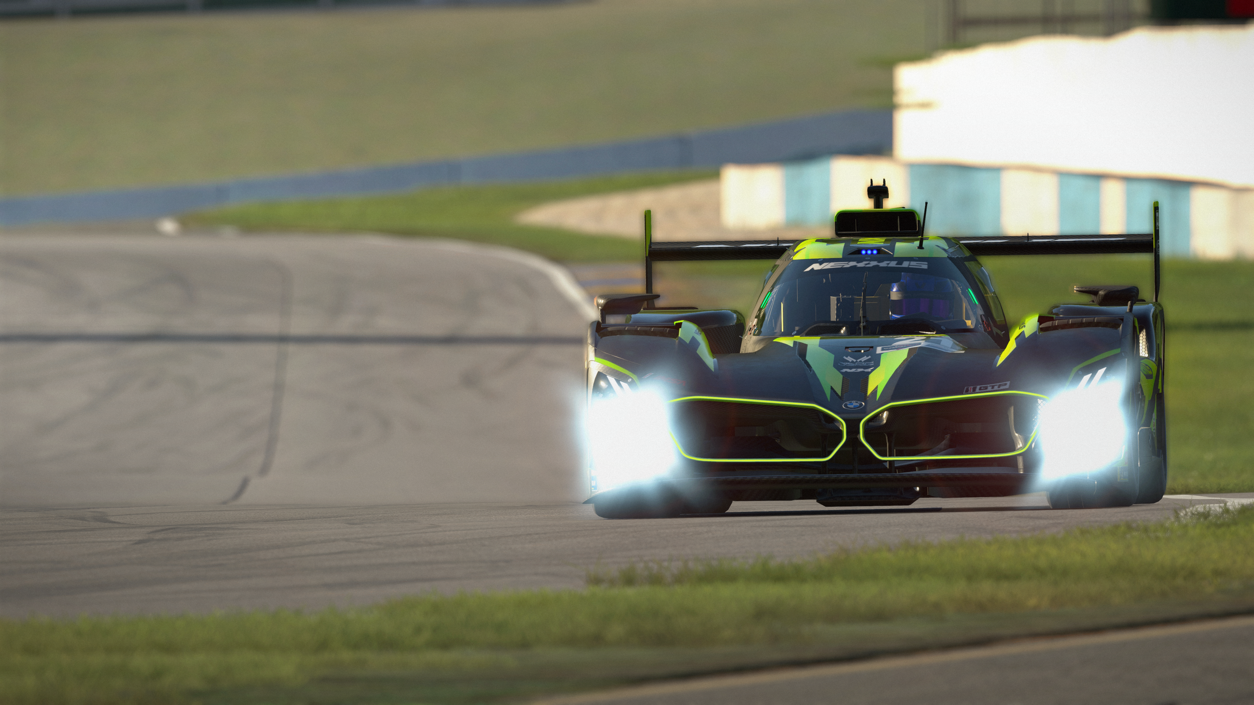 A blue and black race car on a race track during daytime. The car has high-performance racing features, a large rear wing, and various sponsor logos.
