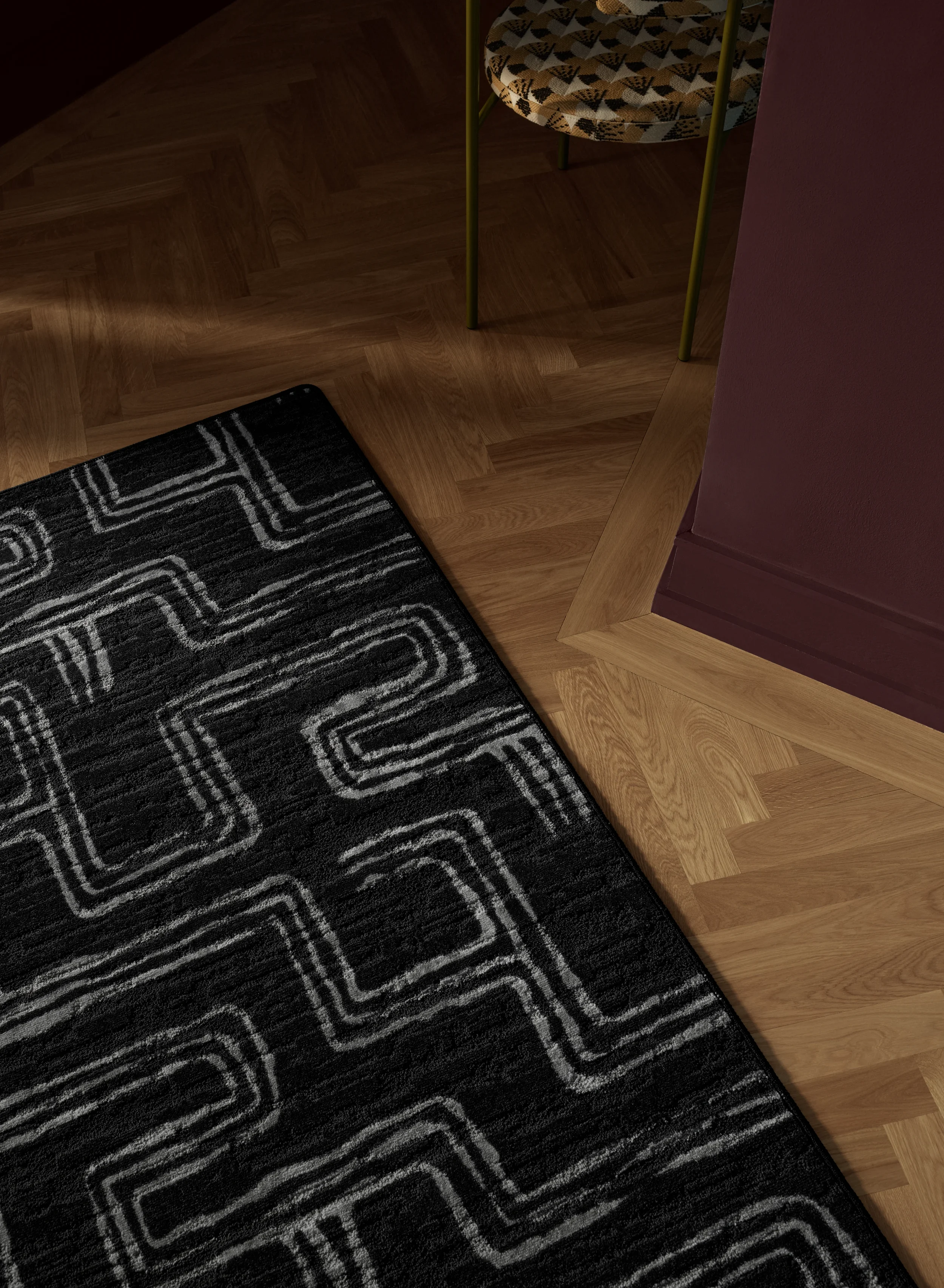 Close-up of a black rug with white geometric patterns on a wooden floor, next to a purple wall and a chair with yellow legs and patterned seat featuring custom area rugs by Matter&co.