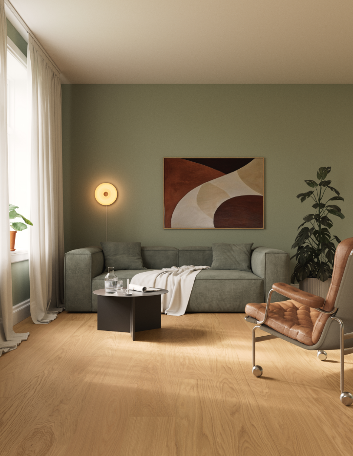 Living room with a green sofa, abstract wall art, a small black coffee table with water and papers, a tan armchair, a potted plant, and a window with white curtains.