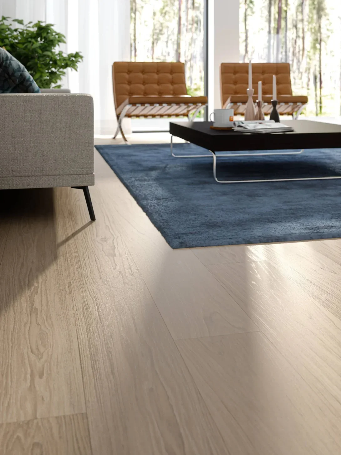Modern living room with beige and brown chairs, a blue area rug, a black coffee table with candles, a cup, and magazines, and large windows with trees outside.