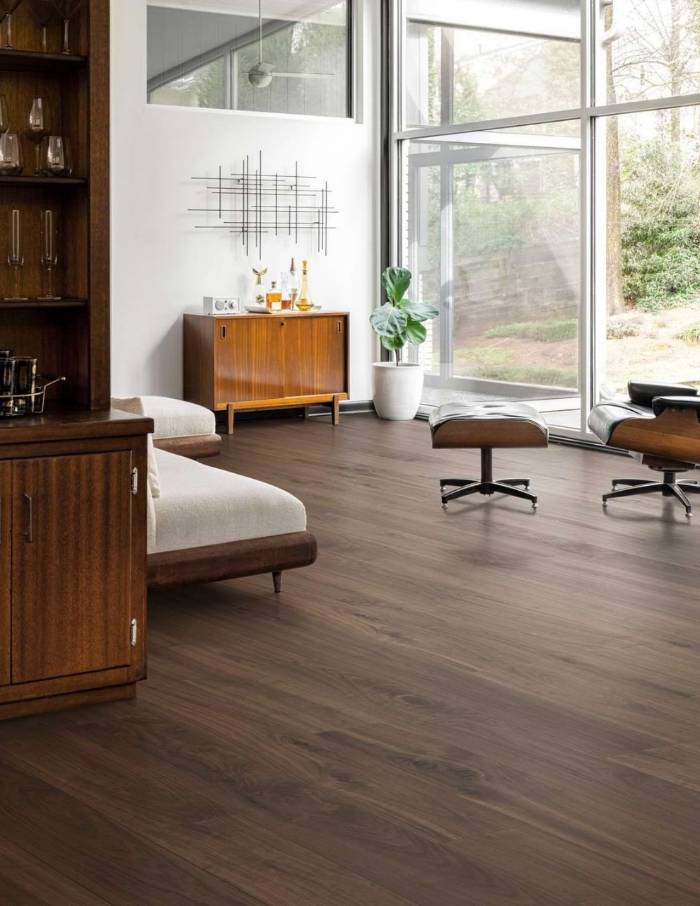 Modern living room with large windows, wooden furniture, and a potted plant, featuring a minimalist decor style.