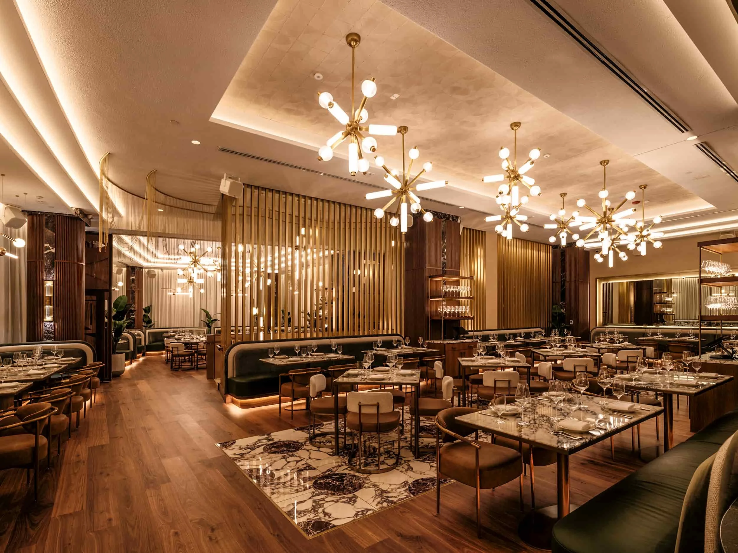 Elegant restaurant interior with wooden flooring, contemporary chandeliers, and stylish seating arrangements with tables set for dining with resilient damage free wood flooring for restaurants.
