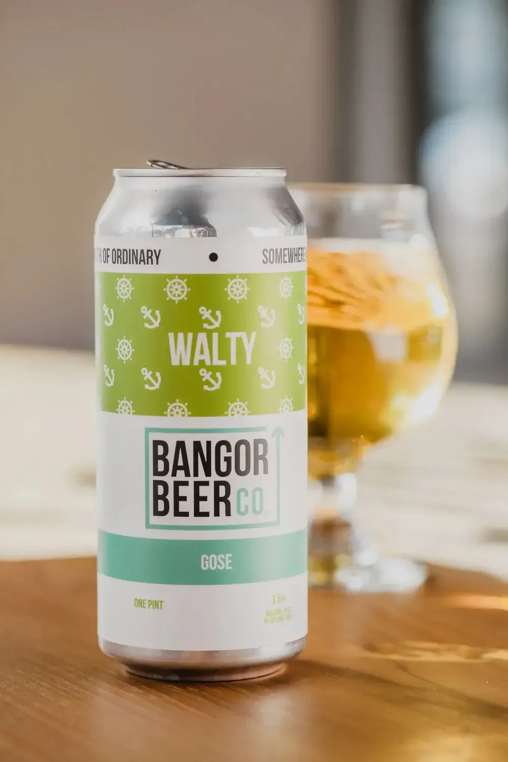  A can of Banger beer rests on a table beside a filled glass of beer, showcasing a casual drinking setting.