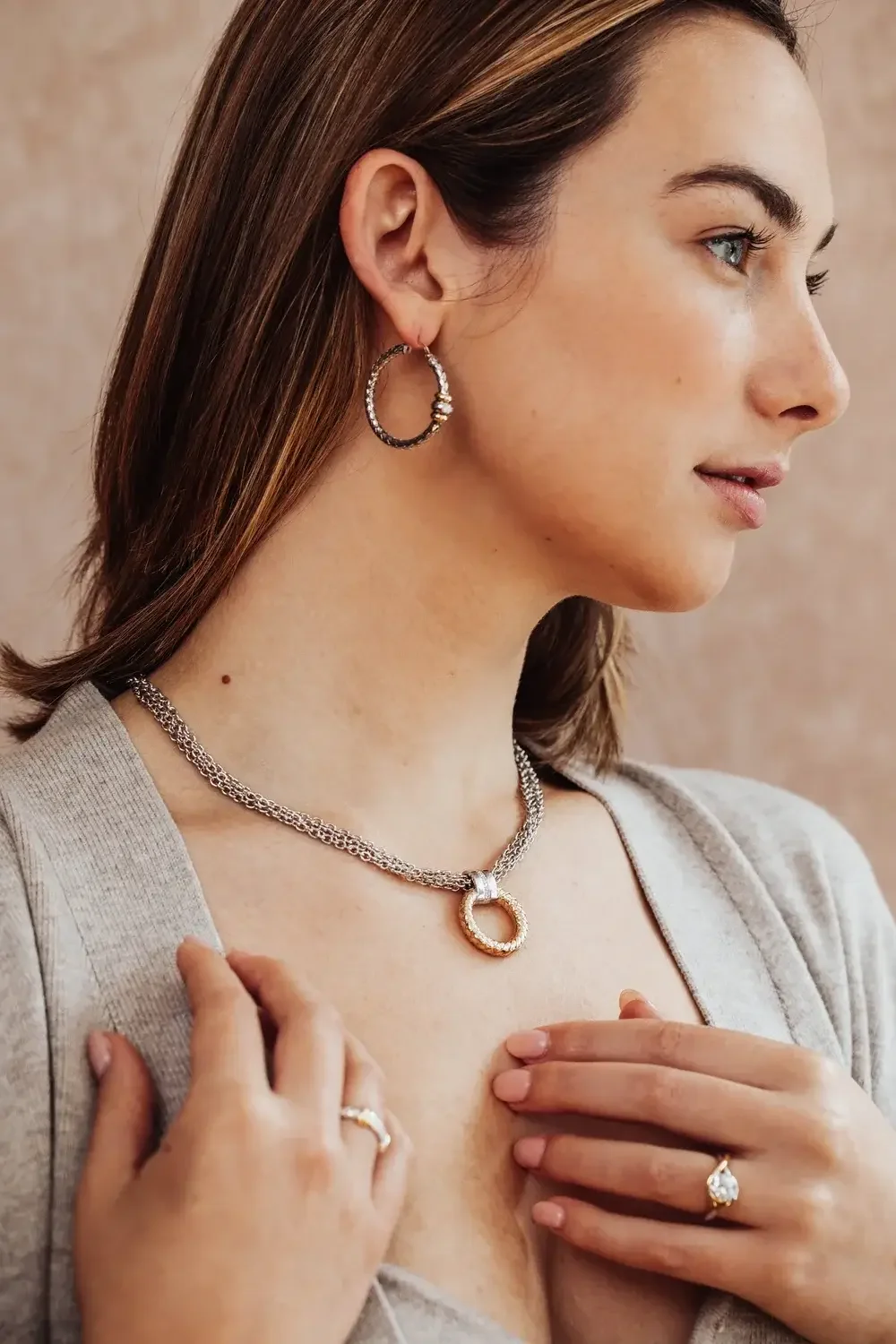  A woman models a necklace and earrings, showcasing elegant jewelry against a neutral background.
