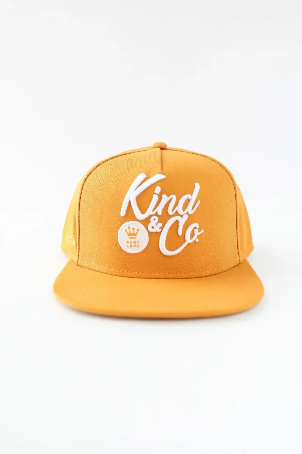 Orange snapback hat featuring the Kind & Co logo prominently displayed on the front.
